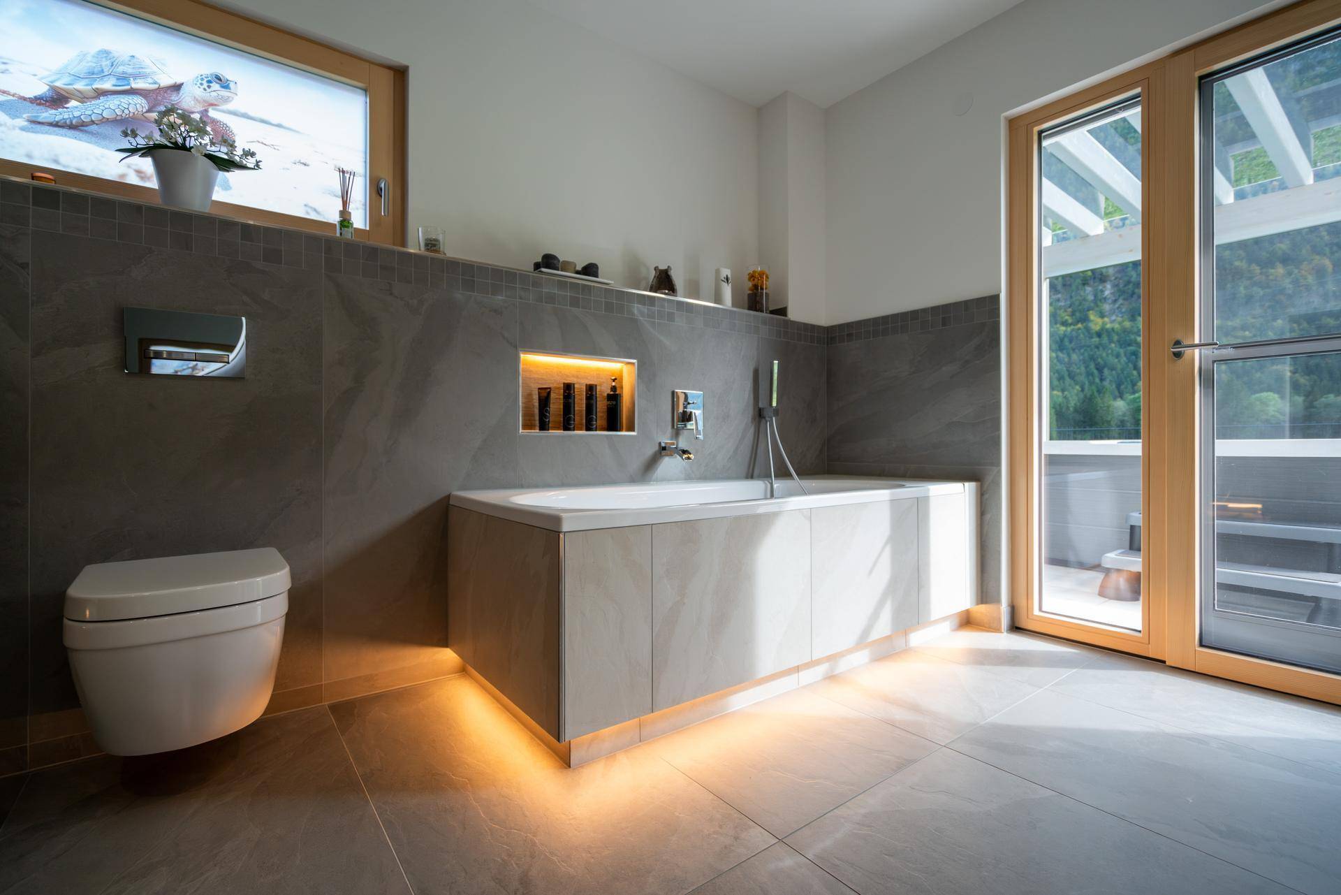 Elegantes Badezimmer mit Badewanne, Wand-WC und Zugang zu einem Außenbereich.