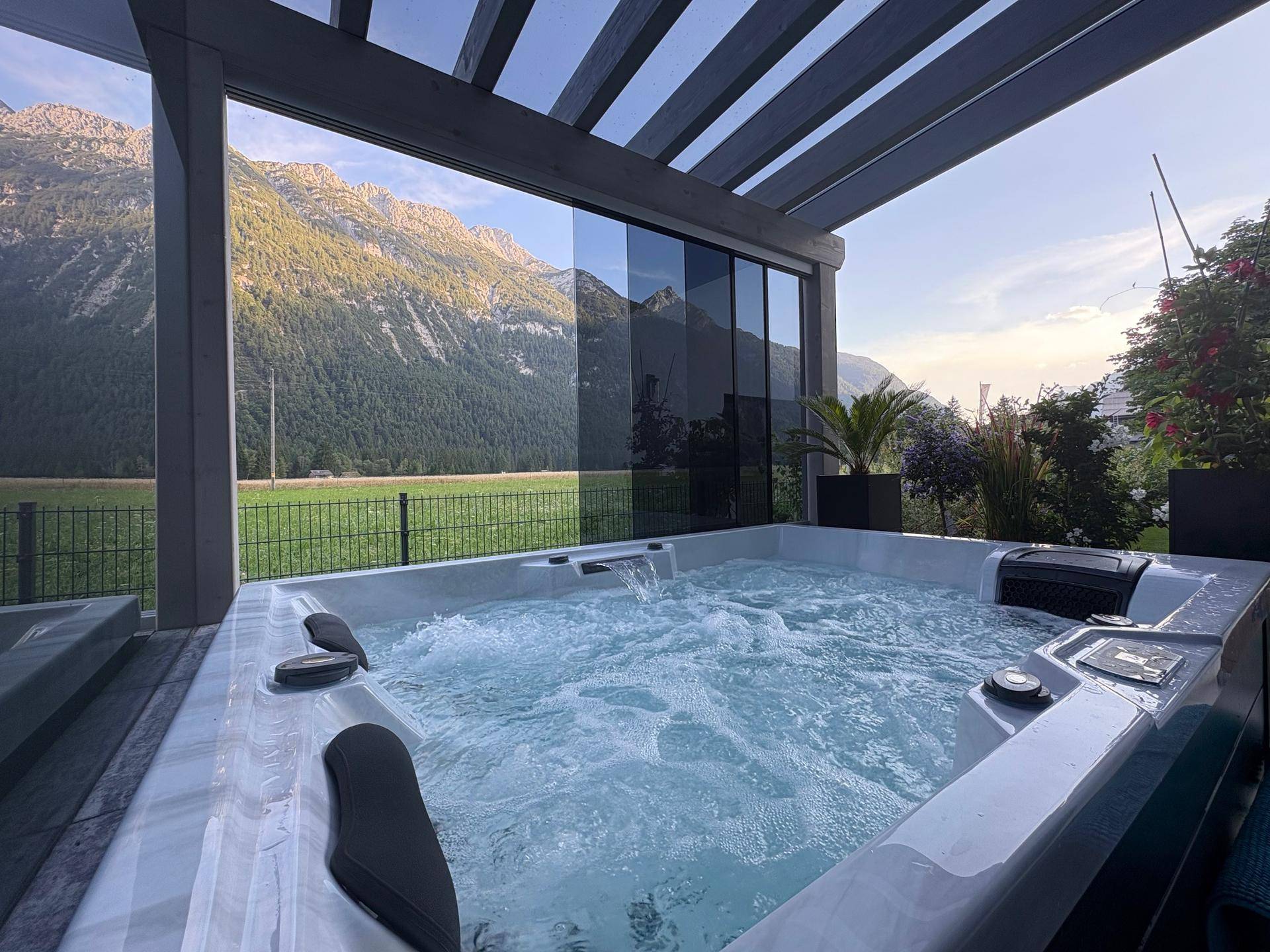 Sprudelnder Außen-Whirlpool mit Panoramablick auf die Berge bei Sonnenuntergang.