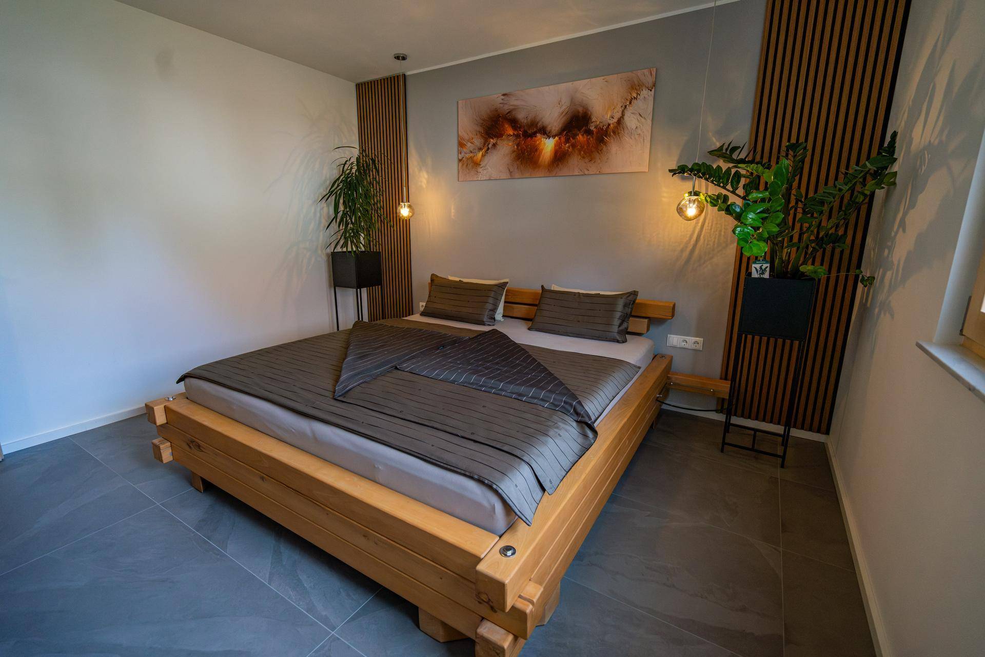 Gemütliches Schlafzimmer mit Holzbett, moderner Kunst und dekorativen Wandpaneelen.