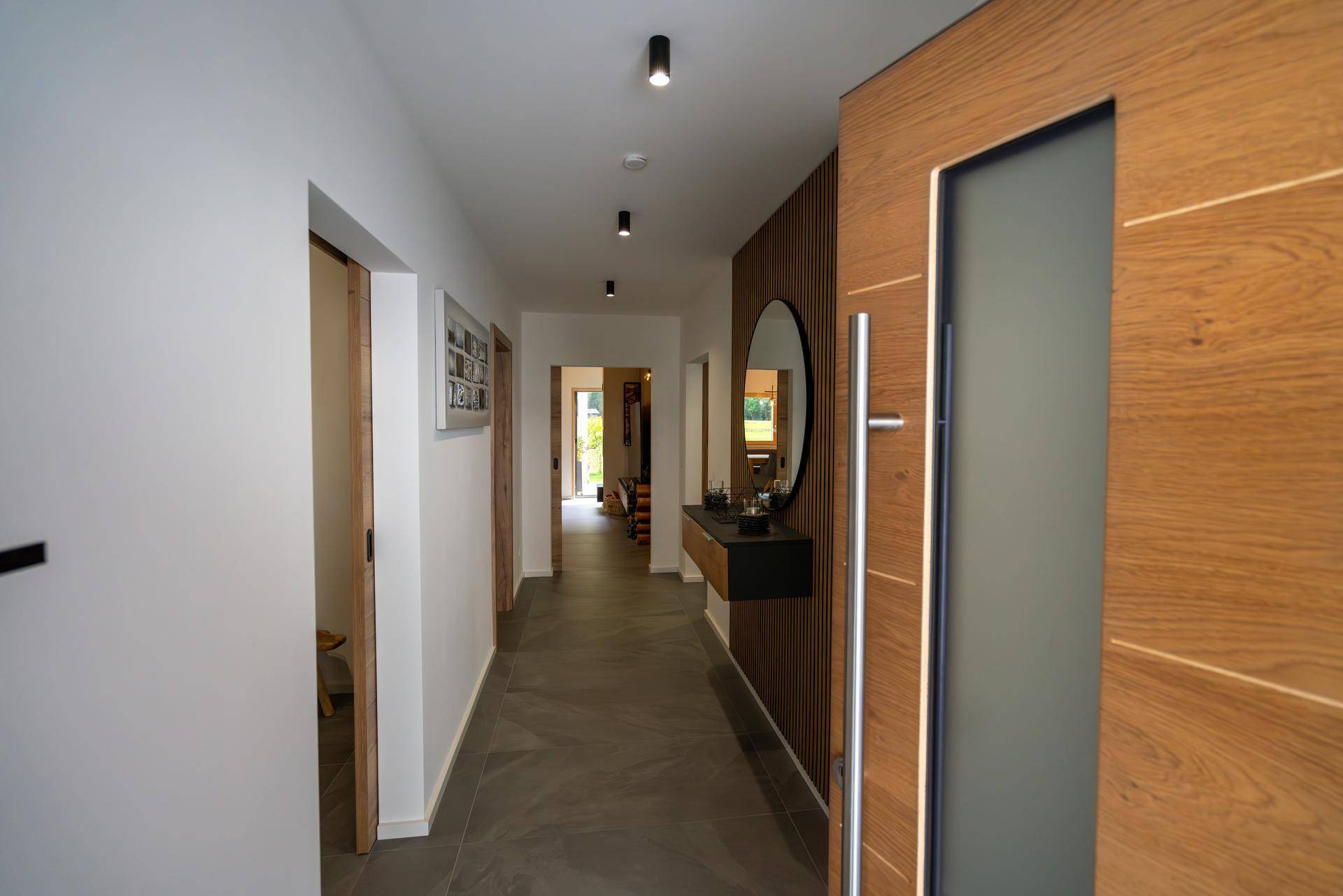 Heller Flur mit Holztüren, modernem Spiegel und Zugang zu verschiedenen Räumen.