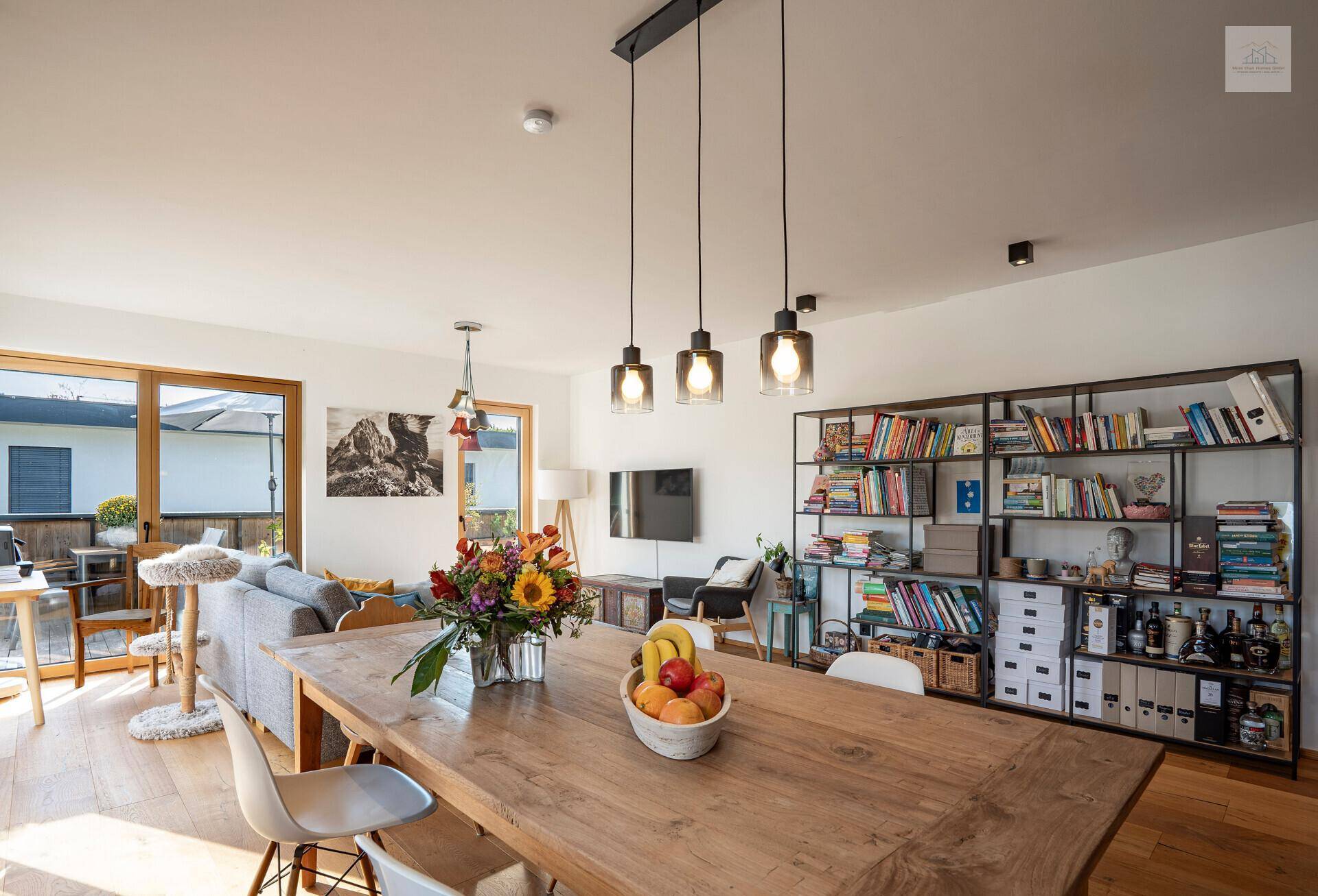 Geräumiger Wohn-Essbereich mit großem Holztisch, Bücherregal und Zugang zur Terrasse.
