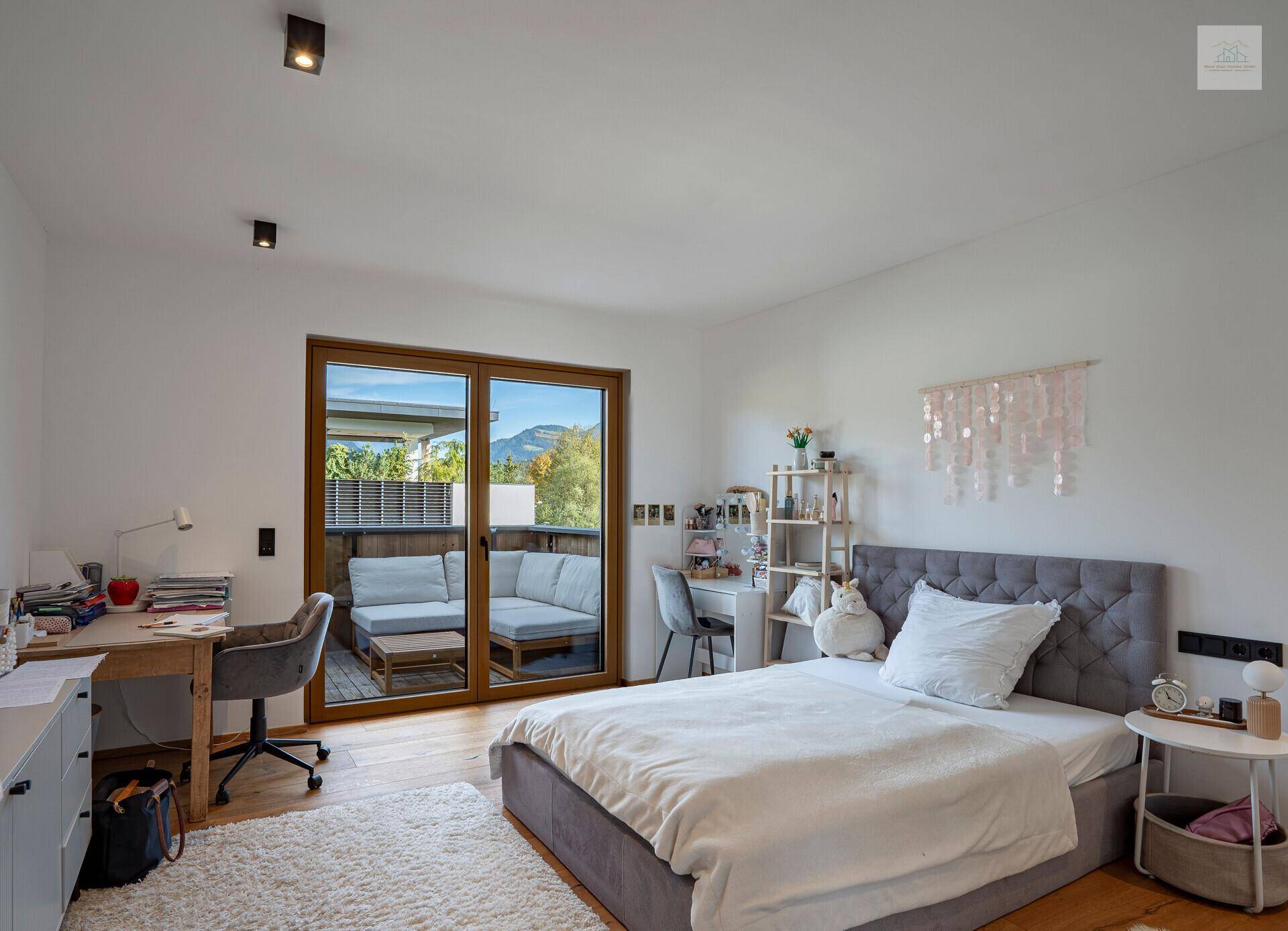 Kinderzimmer mit Bett, Schreibtisch und direktem Zugang zu einem Balkon mit Bergblick.
