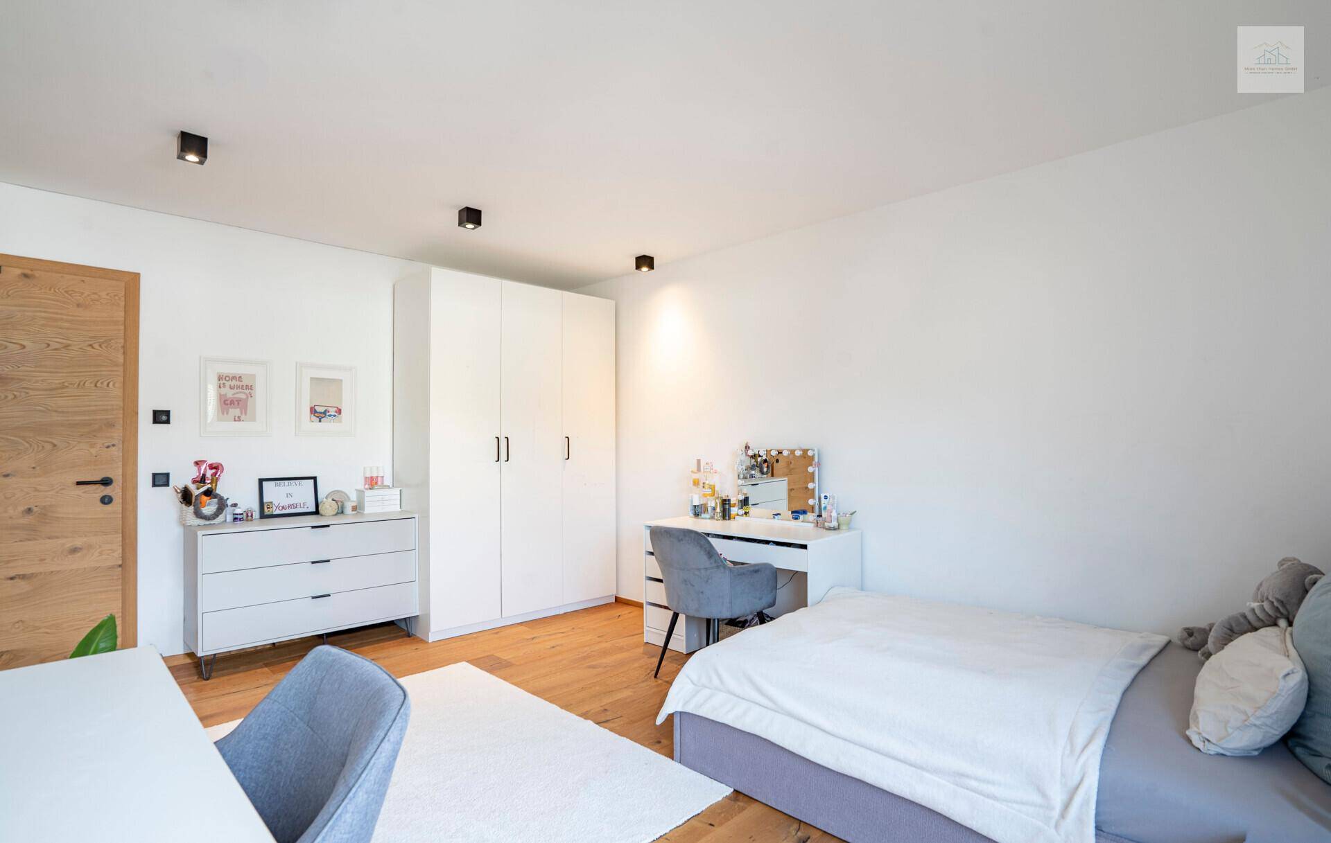 Modern eingerichtetes Kinderzimmer mit Schreibtisch, Kommode und weißem Kleiderschrank.
