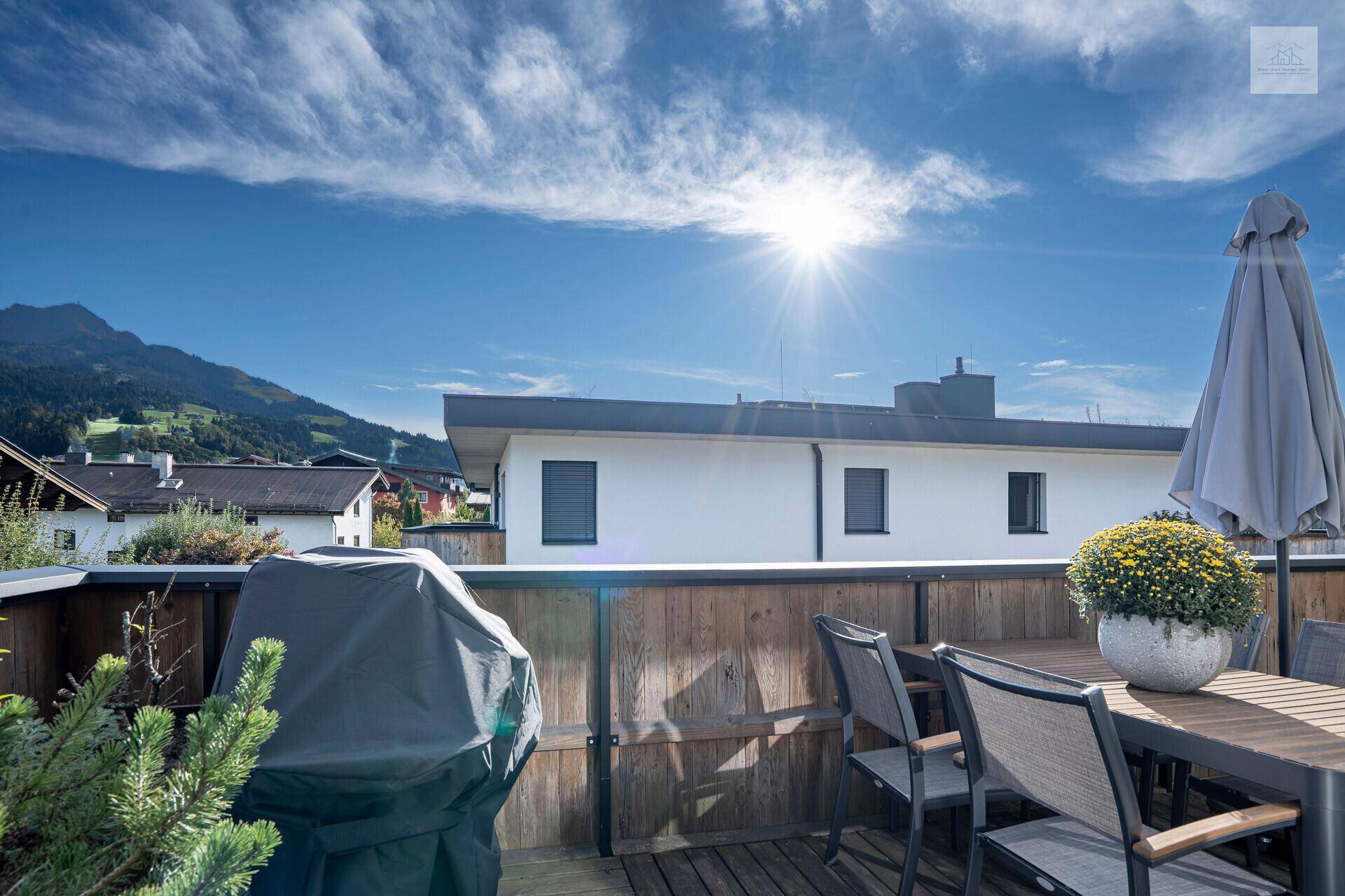 Sonnenterrasse mit Gartenmöbeln, Grill und weitem Blick auf die Berge.