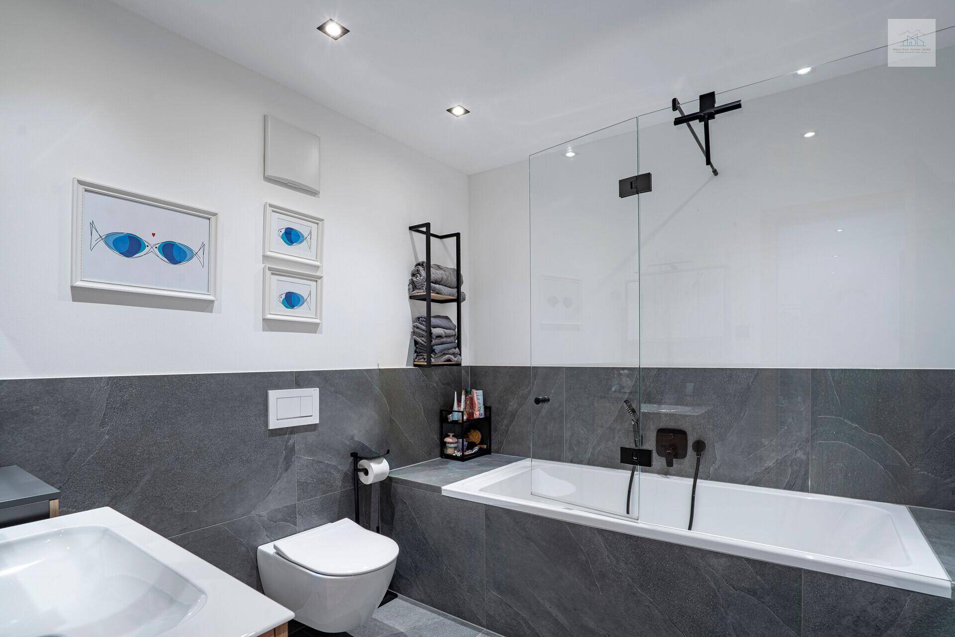 Elegantes Badezimmer mit Badewanne, Dusche und modernen grauen Fliesen.