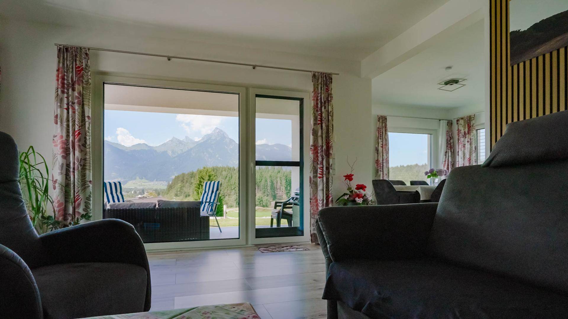 Helles Wohnzimmer mit großen Schiebetüren, die einen atemberaubenden Blick auf die umliegende Bergwelt bieten.