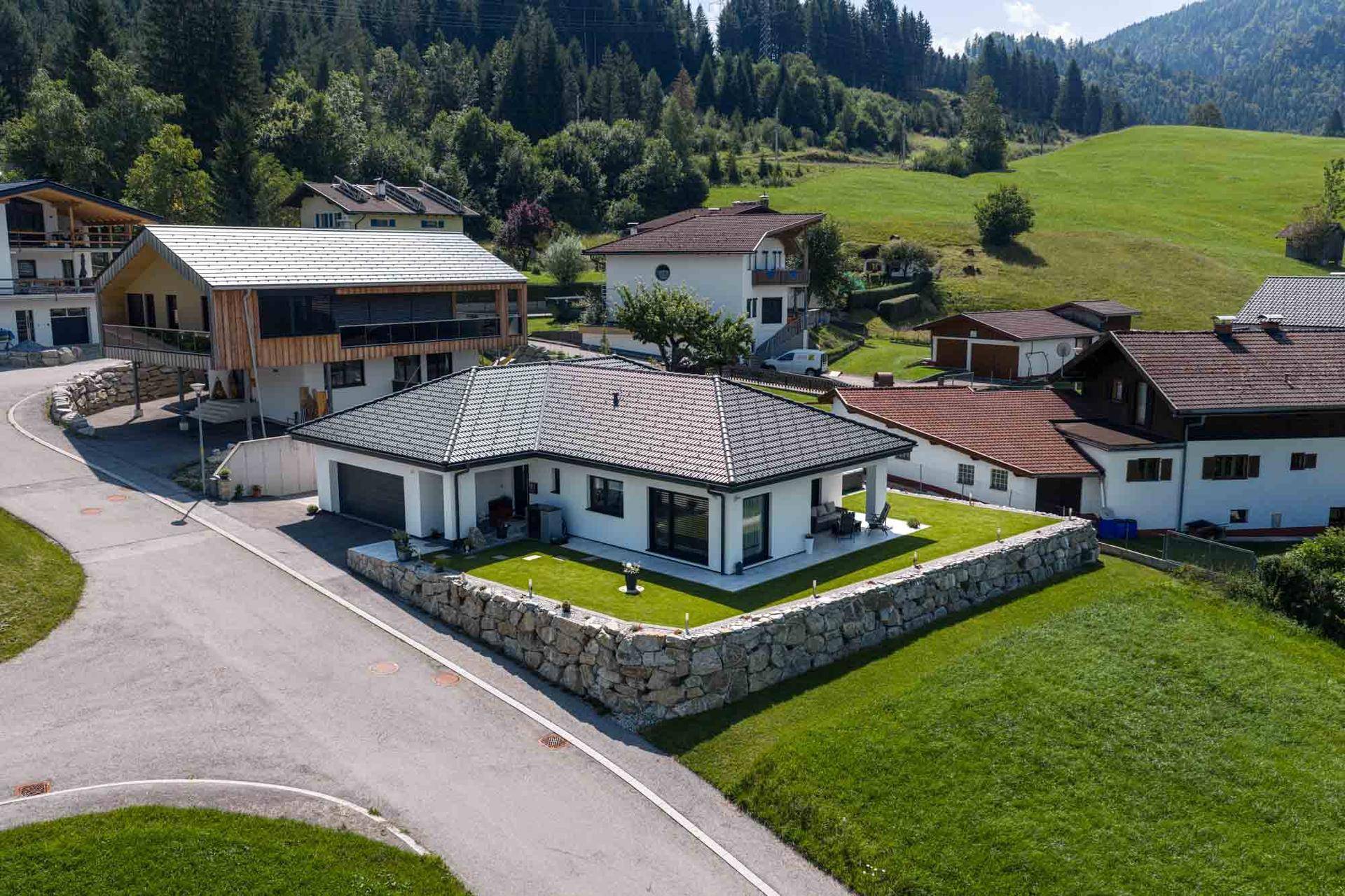 Weitläufige Ansicht des Hauses mit Garage, Zufahrt und der malerischen Berglandschaft im Hintergrund.