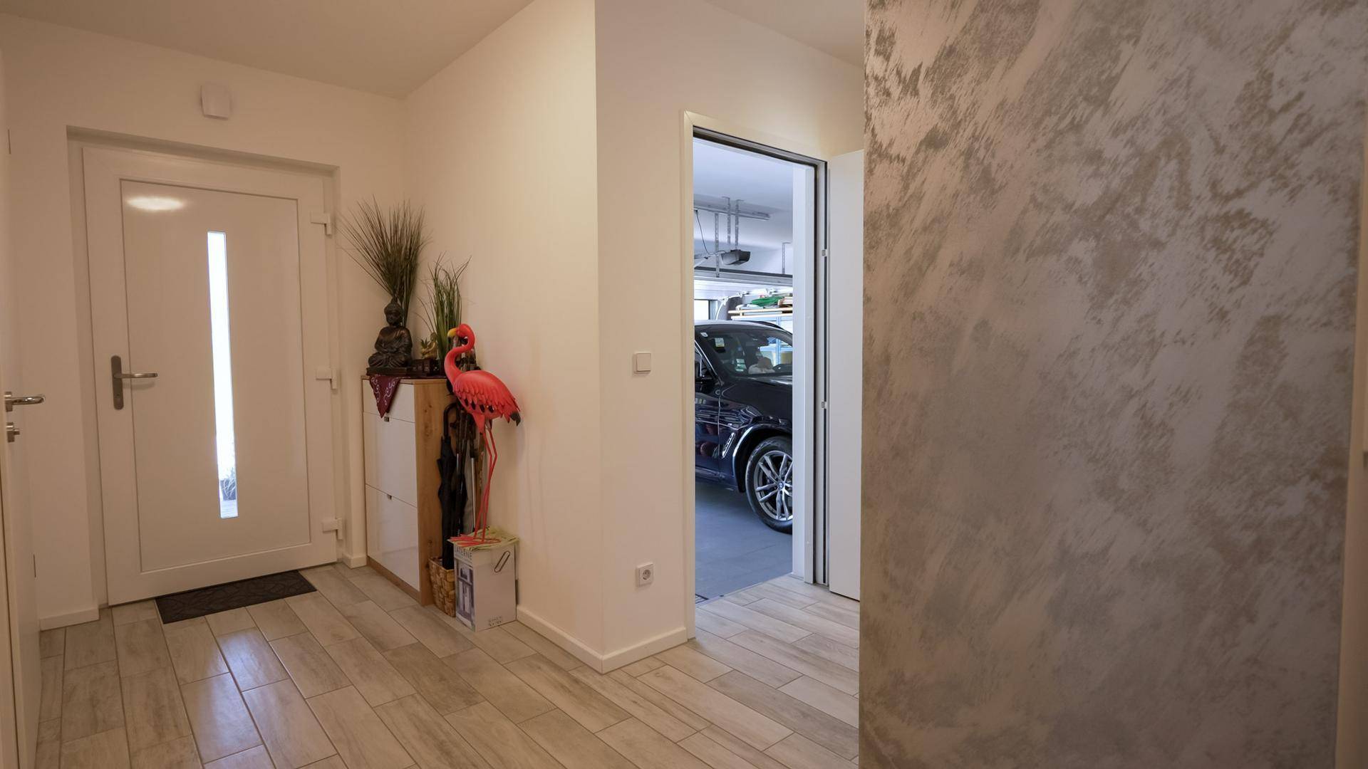 Heller Eingangsbereich mit modernen Dekorationselementen und direktem Zugang zur Garage.