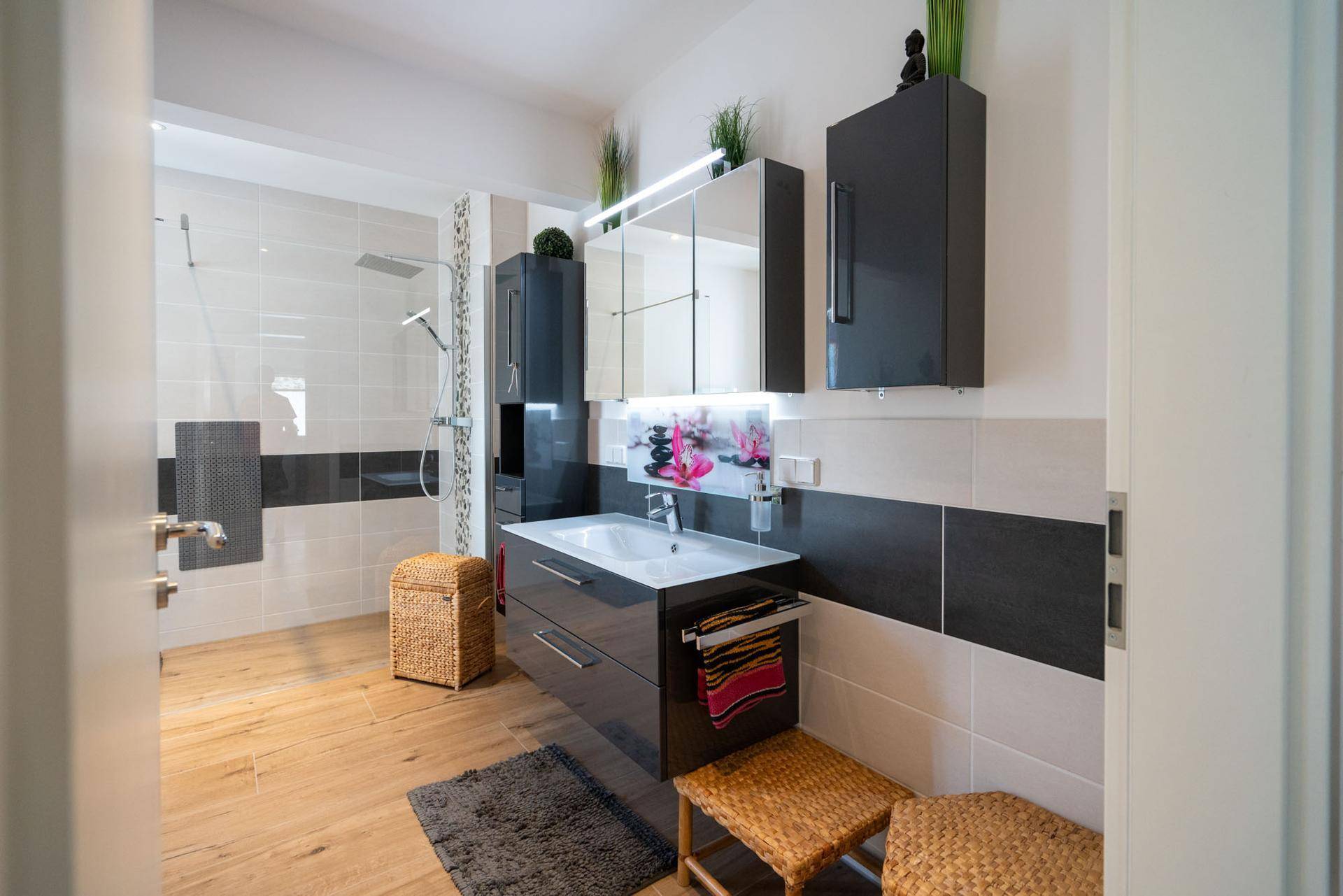 Elegantes Badezimmer mit Waschtisch, Spiegelschrank und begehbarer Dusche.