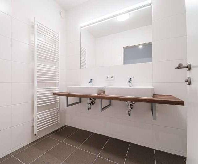 Modernes Badezimmer mit Doppelwaschbecken, großem Spiegel und beheiztem Handtuchhalter.