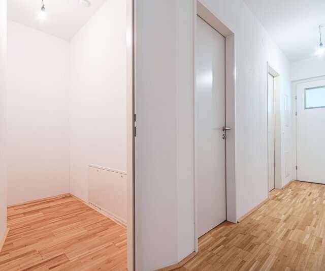 Heller Flur mit Holzboden und mehreren Türen, der zu verschiedenen Räumen führt.