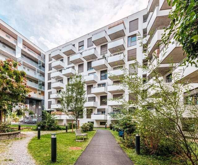 Gepflegter Innenhof mit Grünflächen, Bäumen und Wegen zwischen den Gebäuden.