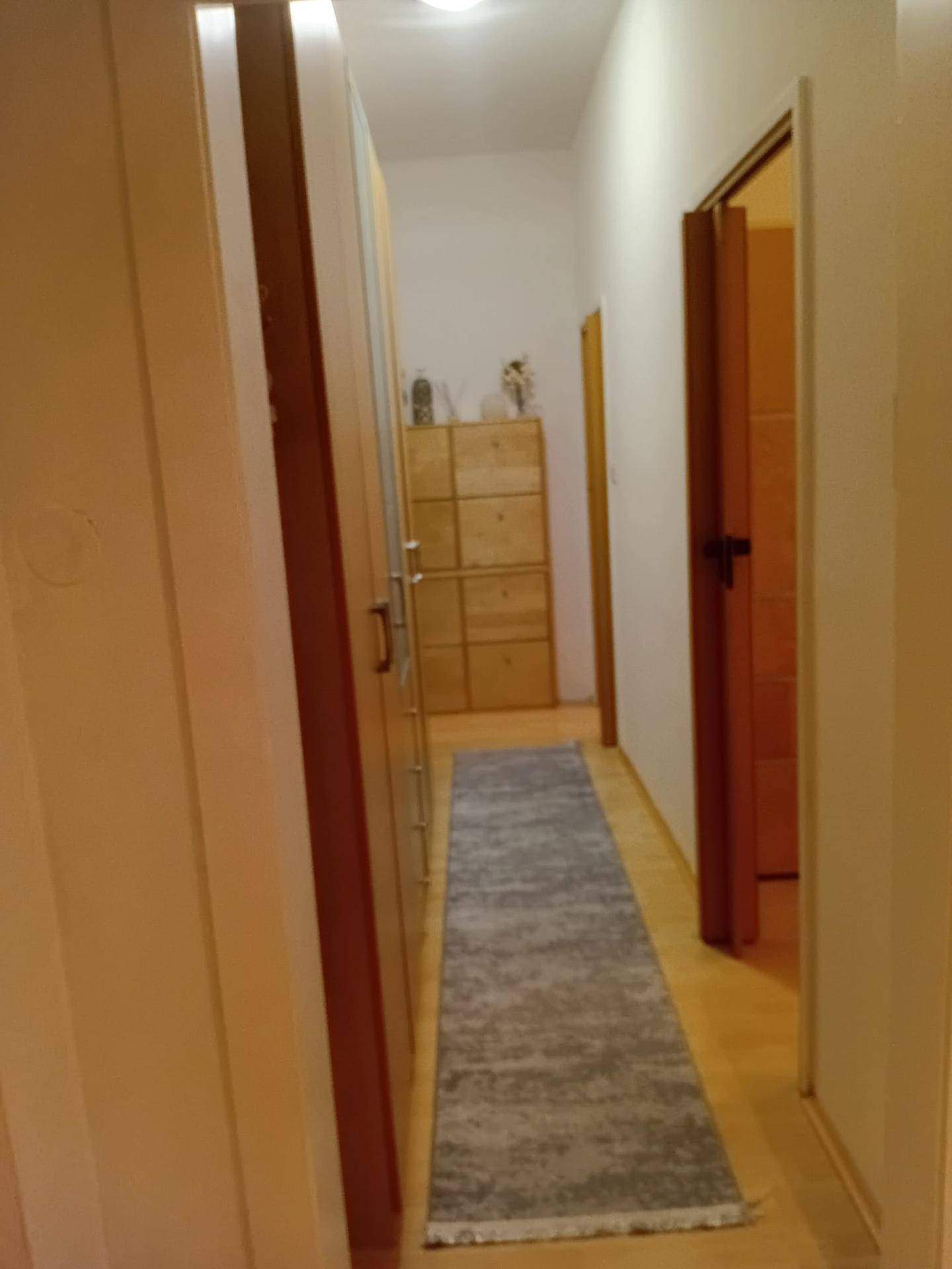 Langer Flur mit Holzfußboden, Teppichläufer und praktischen Holzschränken.