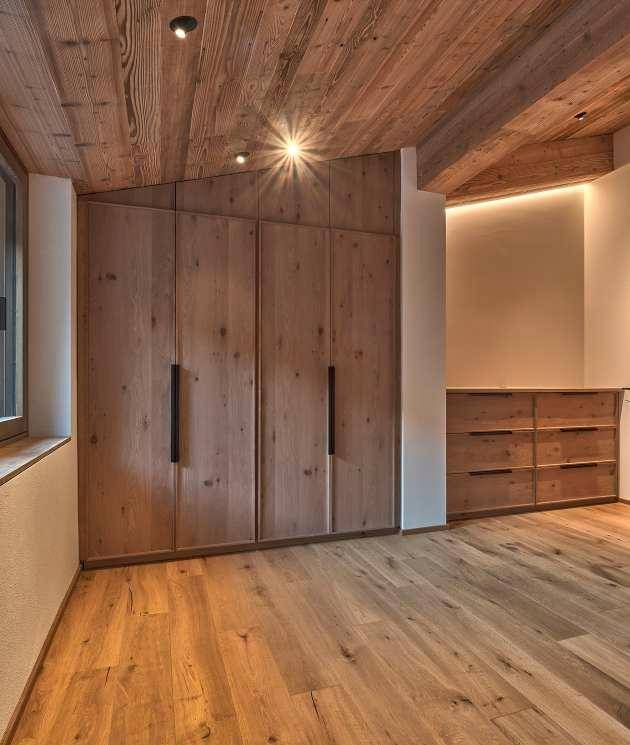 Schlafzimmer mit Holzboden, Holzwänden und maßgefertigten Einbauschränken.