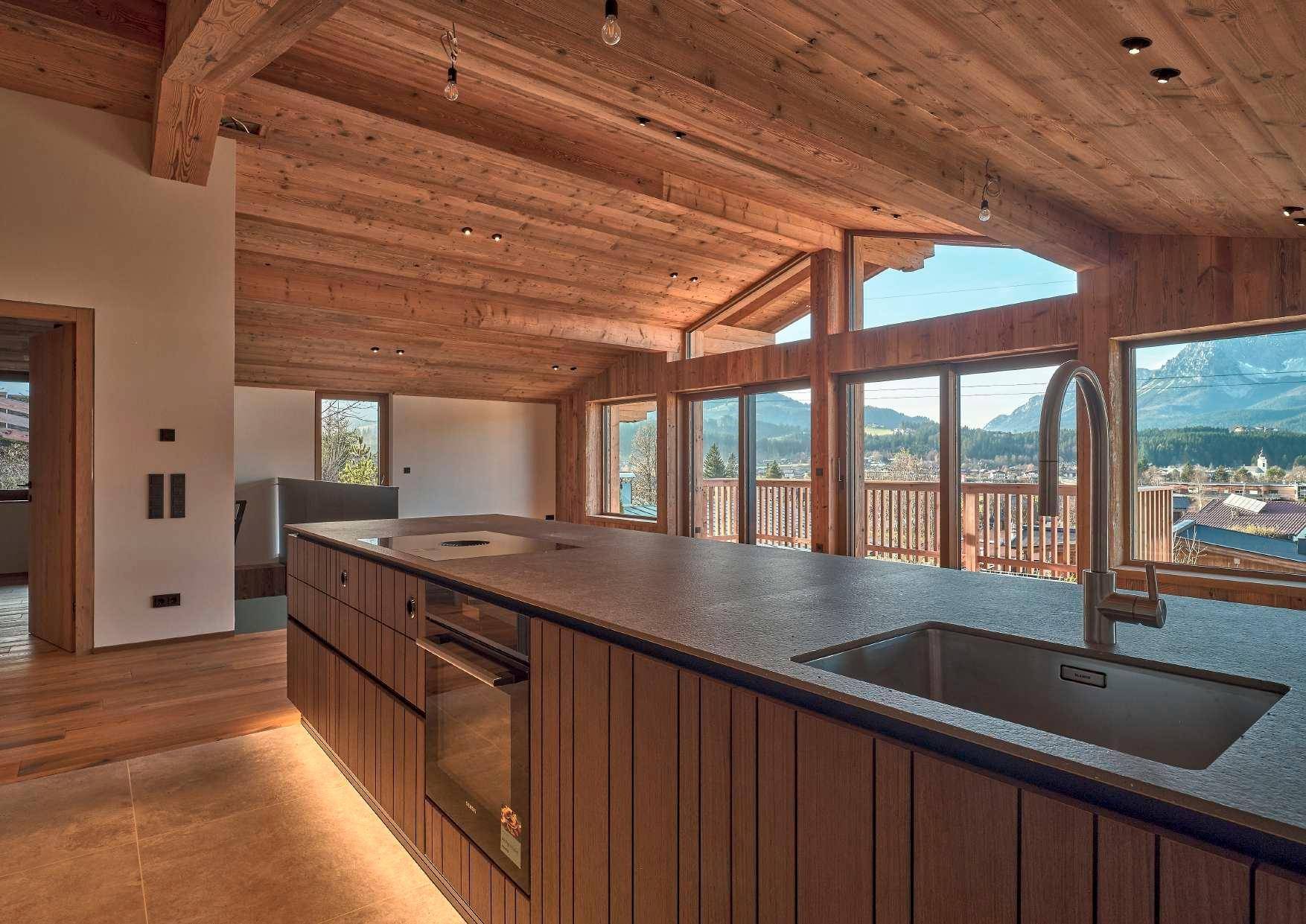 Moderne Küche mit Kochinsel, Spüle und Bergblick durch große Fenster.