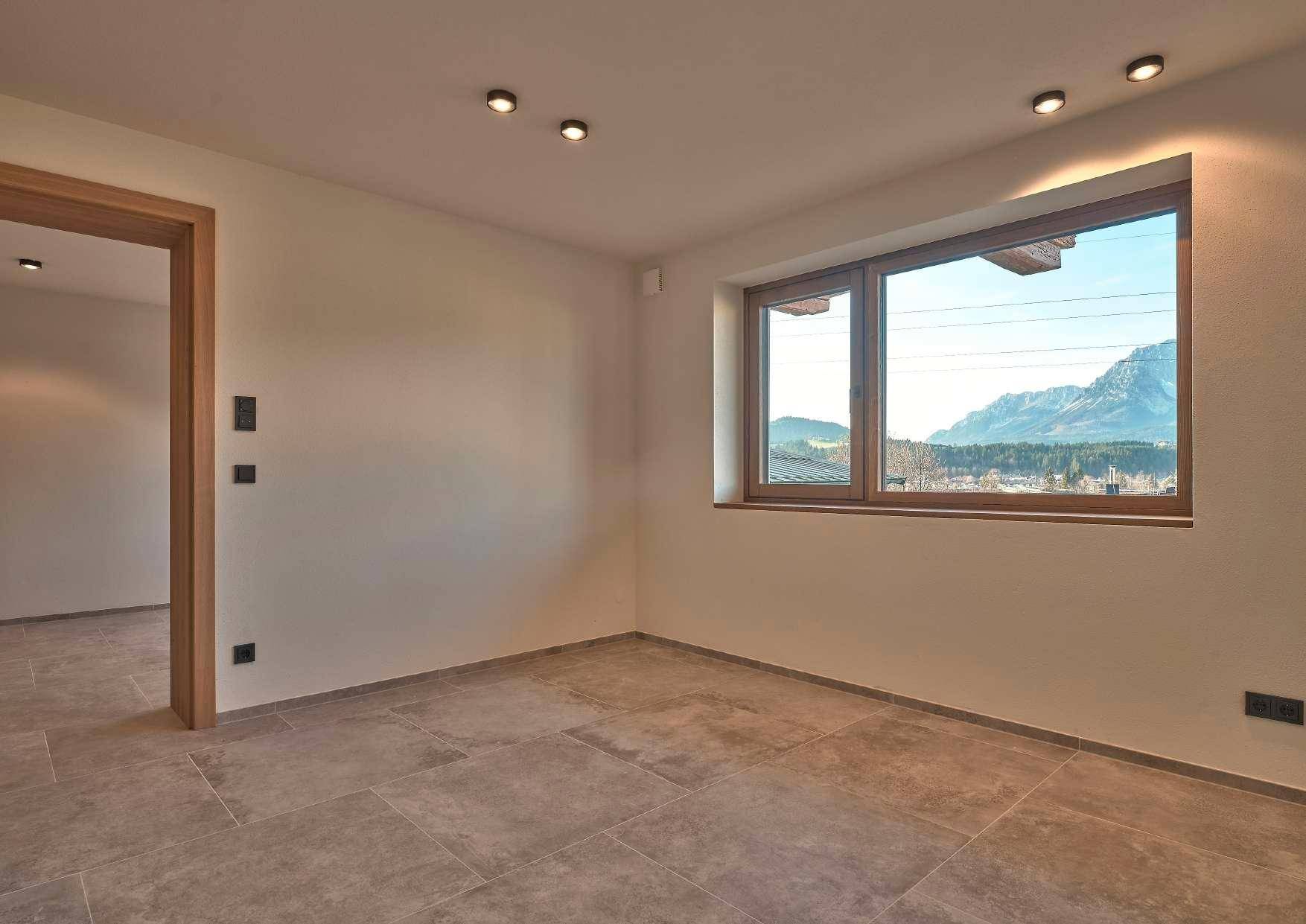 Zimmer mit Fliesenboden und Fenster mit Bergblick, ideal als Schlaf- oder Gästezimmer.