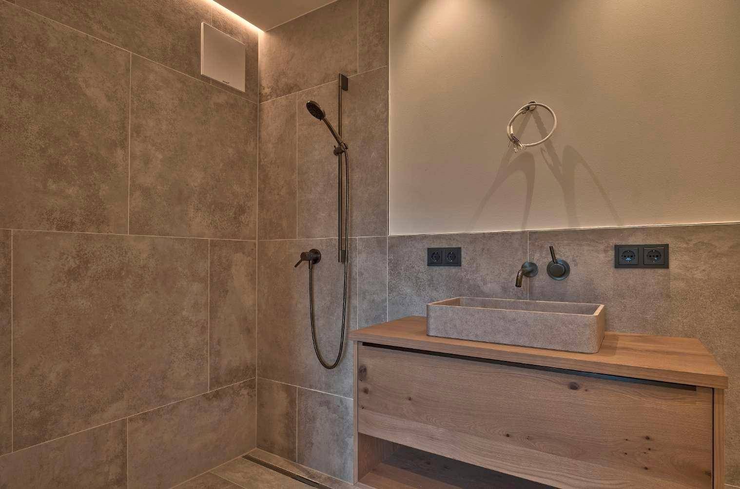 Modernes Badezimmer mit begehbarer Dusche und stilvollem Steinwaschbecken auf Holzunterschrank.