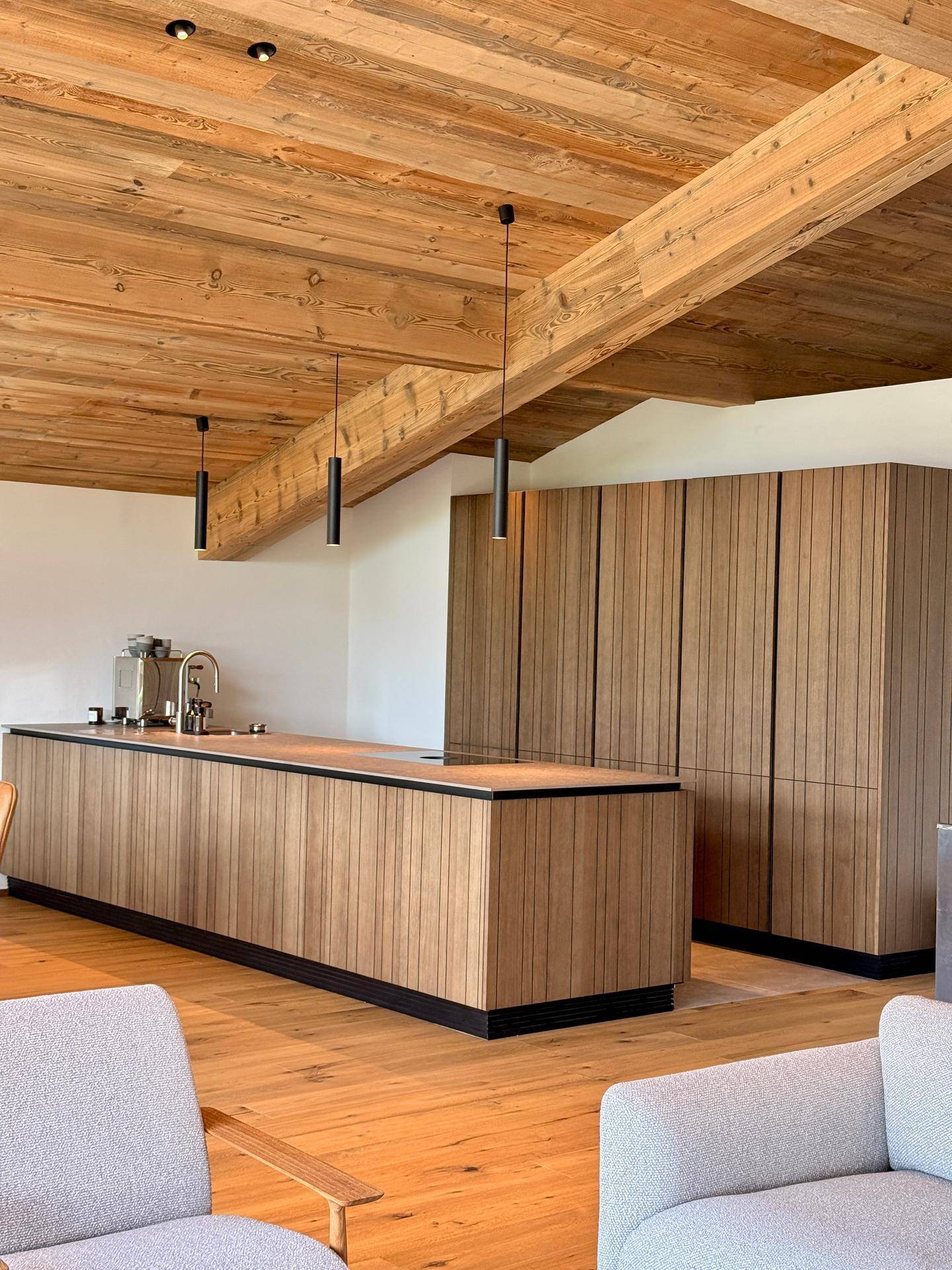 Moderne offene Küche mit Holzfronten, Kochinsel und integrierten Geräten im Wohnbereich.
