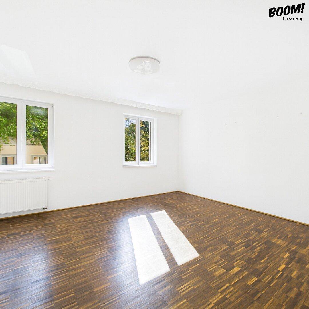 Leeres Schlafzimmer mit Holzboden und zwei Fenstern, bietet viel Potenzial für Gestaltung.
