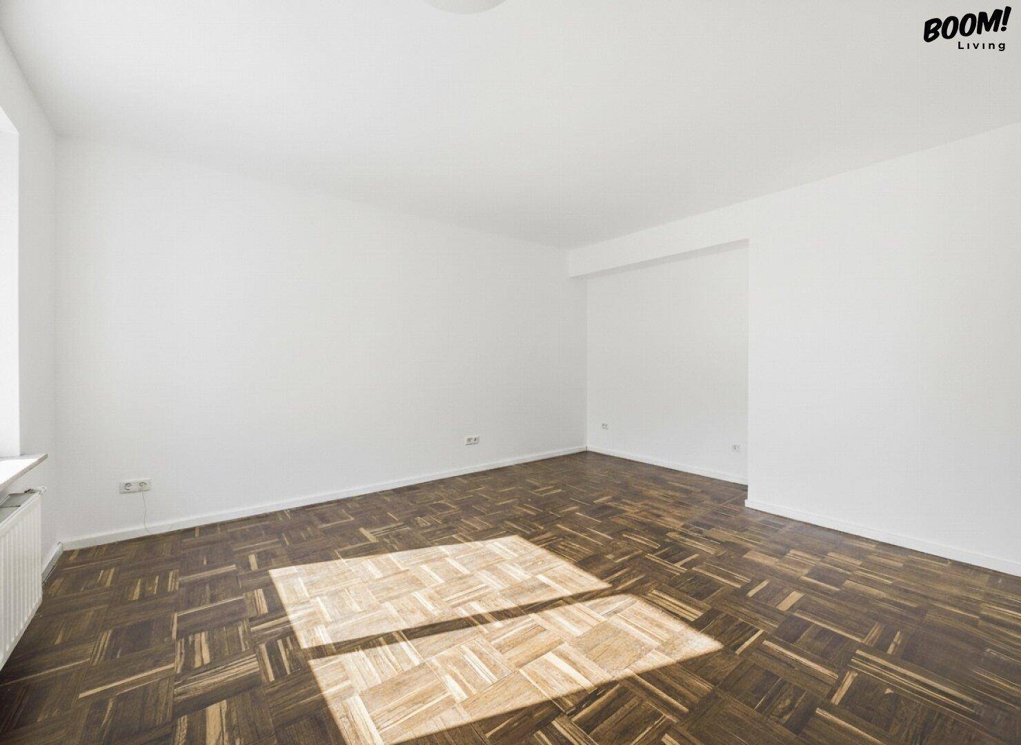 Geräumiger, leerer Raum mit Holzboden und viel Tageslicht, ideal für Wohn- oder Schlafzimmer.