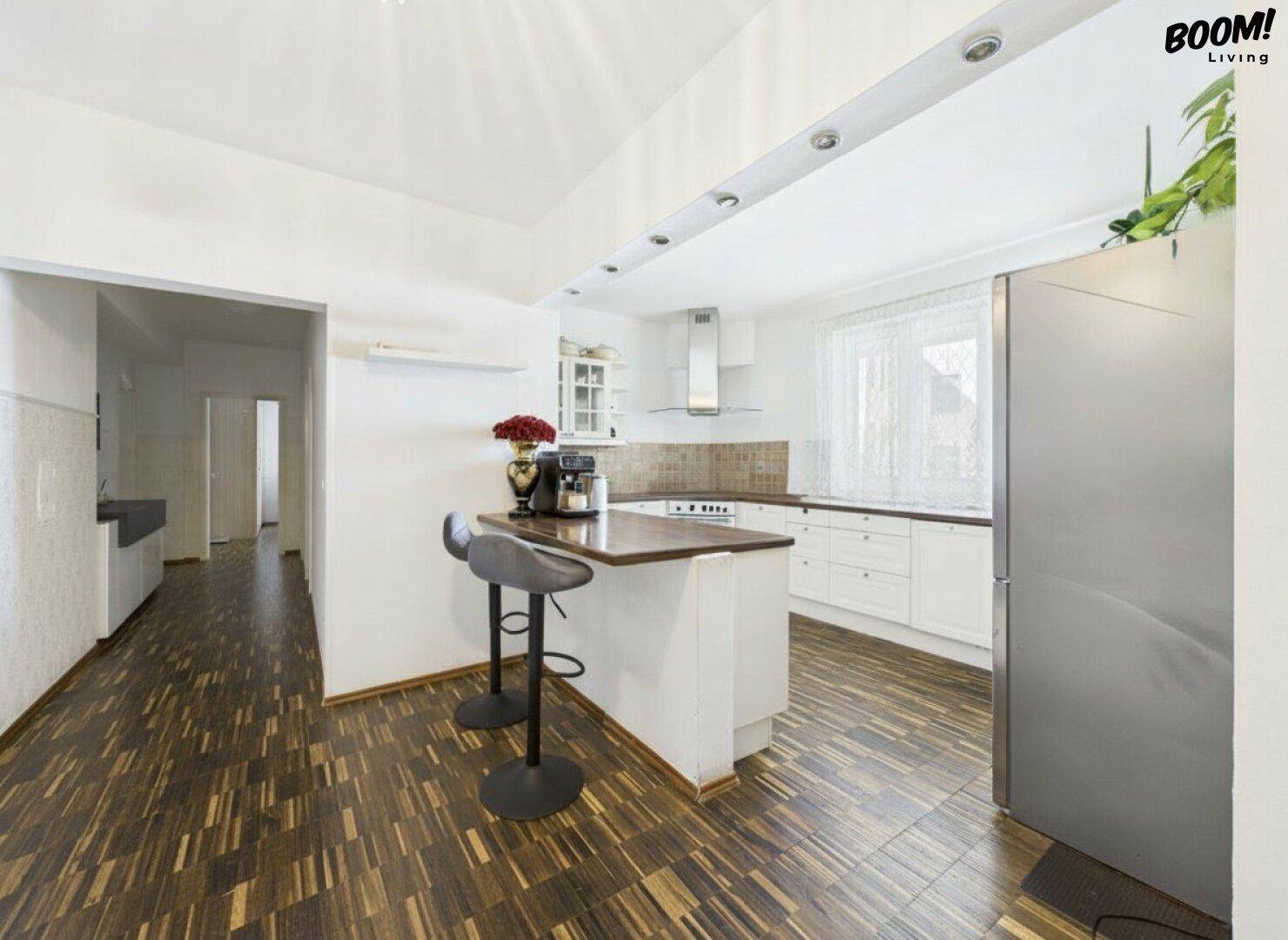 Funktionale Küche mit Holzboden, Frühstücksbar und modernen Geräten, gut beleuchtet.