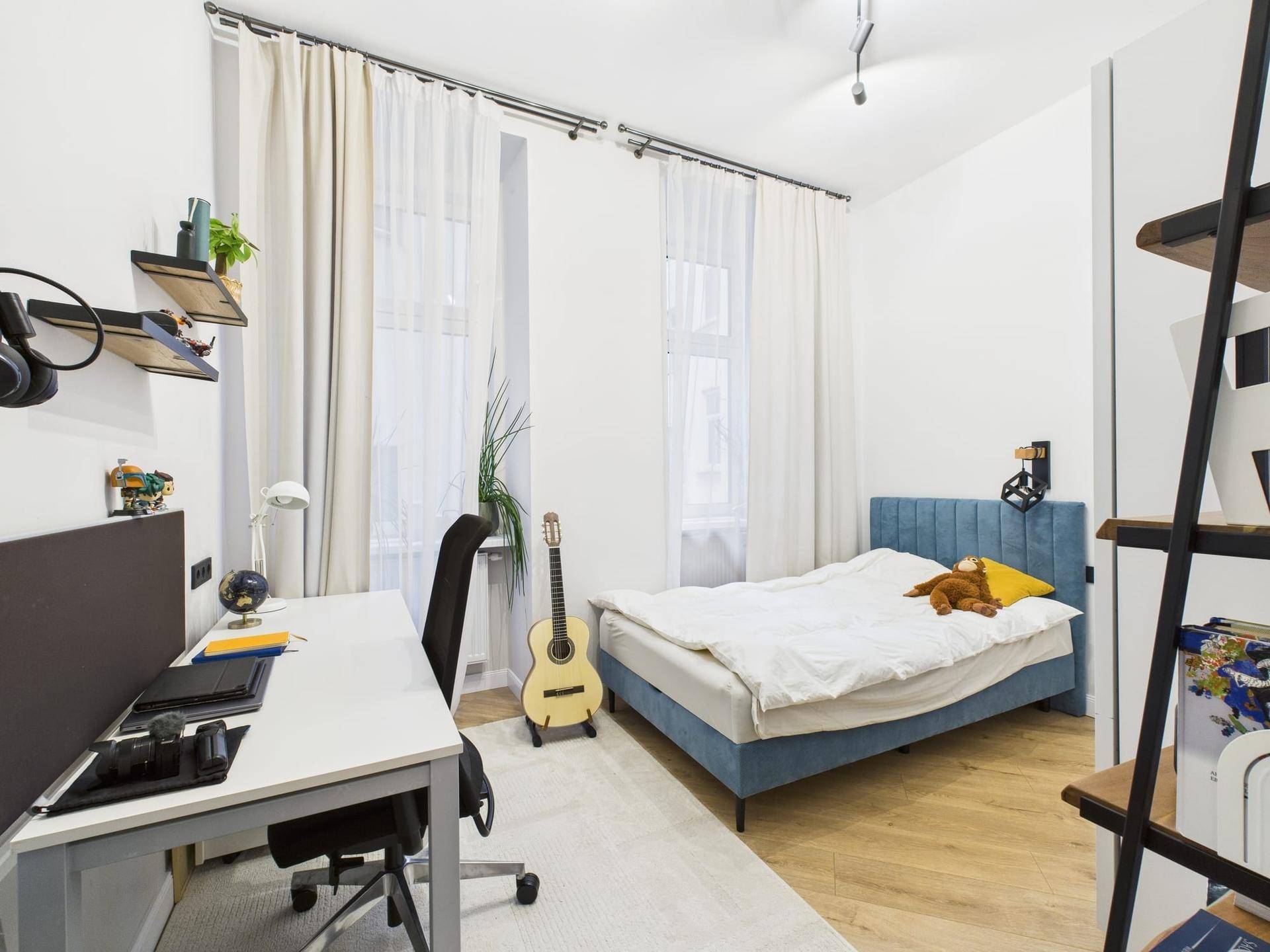 Helles Schlafzimmer mit Einzelbett, Schreibtisch und Fenster, ideal für Kinder oder Gäste.