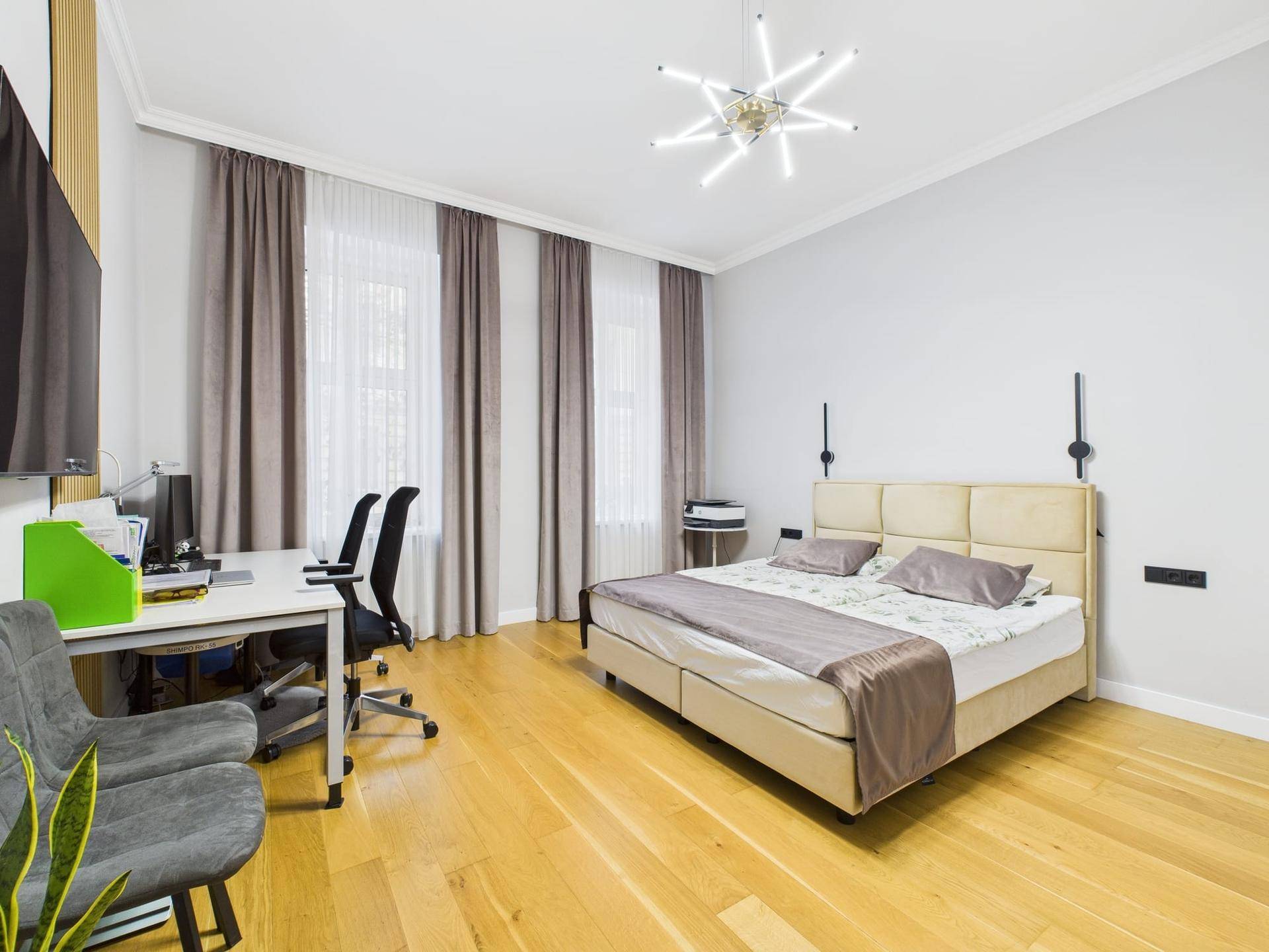 Geräumiges Schlafzimmer mit Doppelbett, Schreibtisch und hellem Holzfußboden.