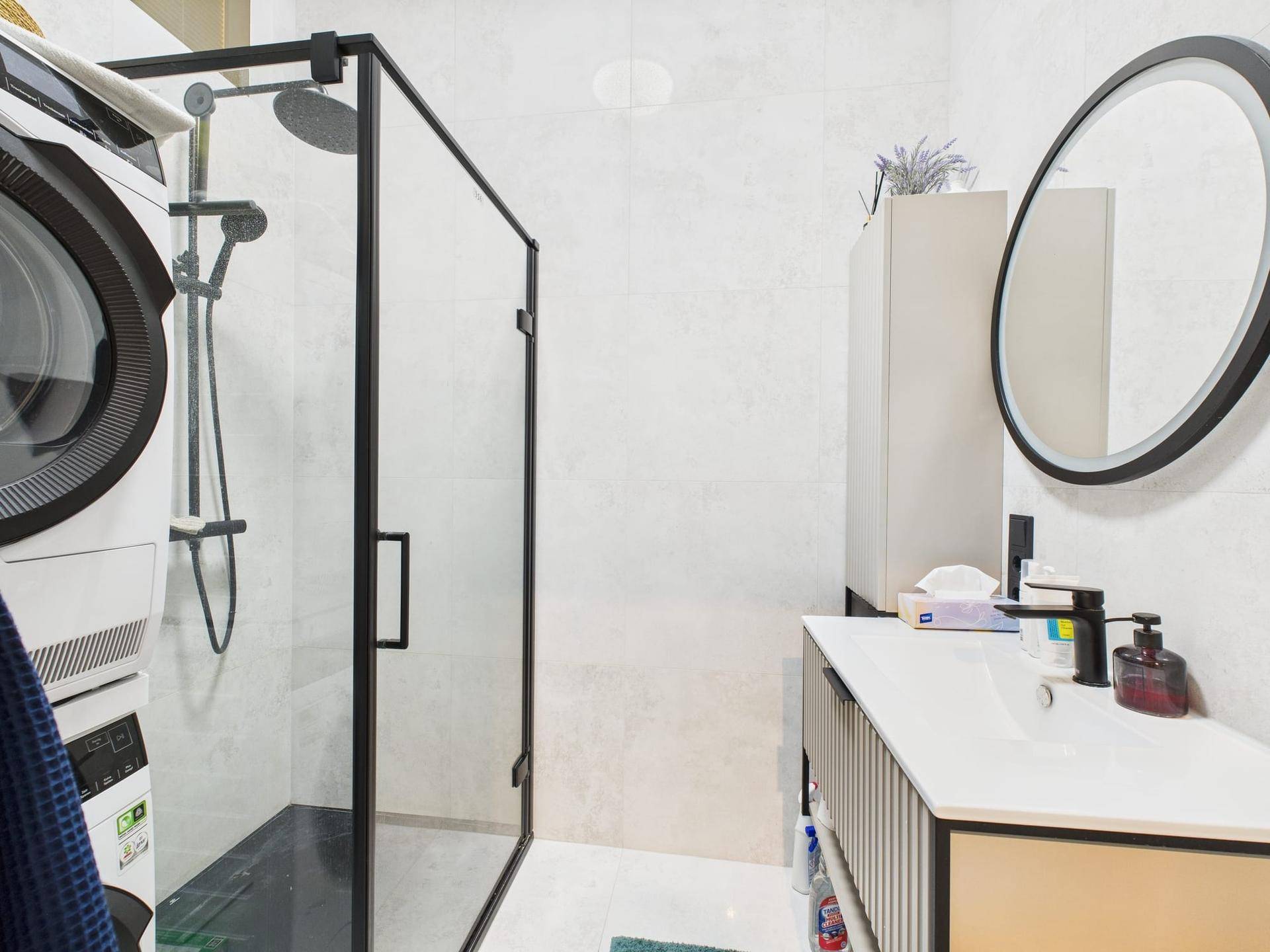 Modernes Badezimmer mit begehbarer Dusche, Waschbecken und integrierter Waschmaschine.