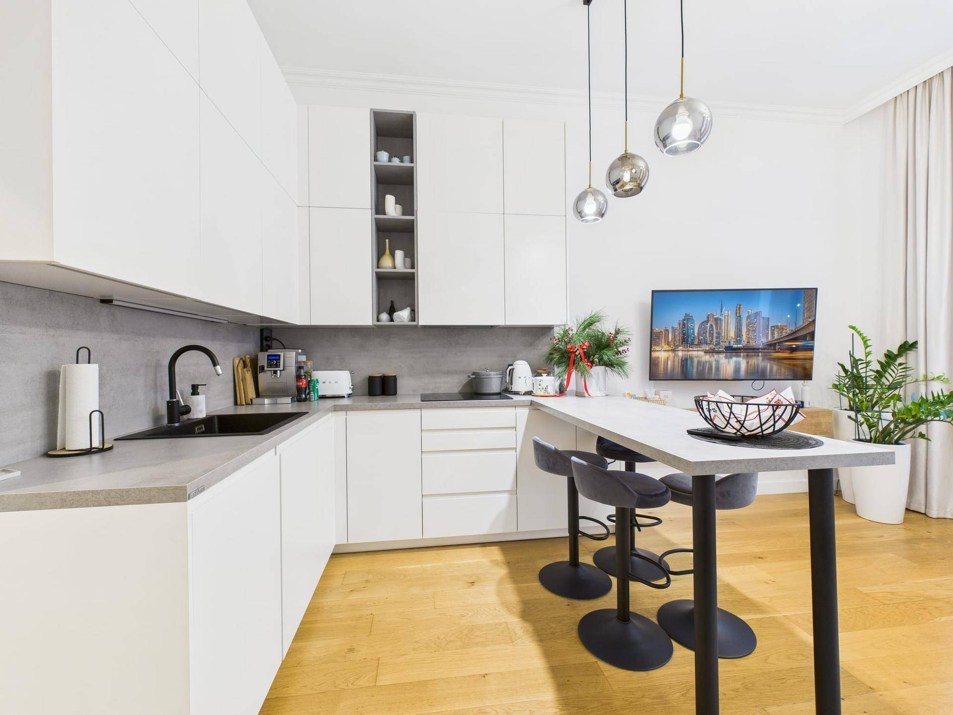 Moderne Einbauküche mit weißen Schränken, grauer Arbeitsplatte und Bartresen.