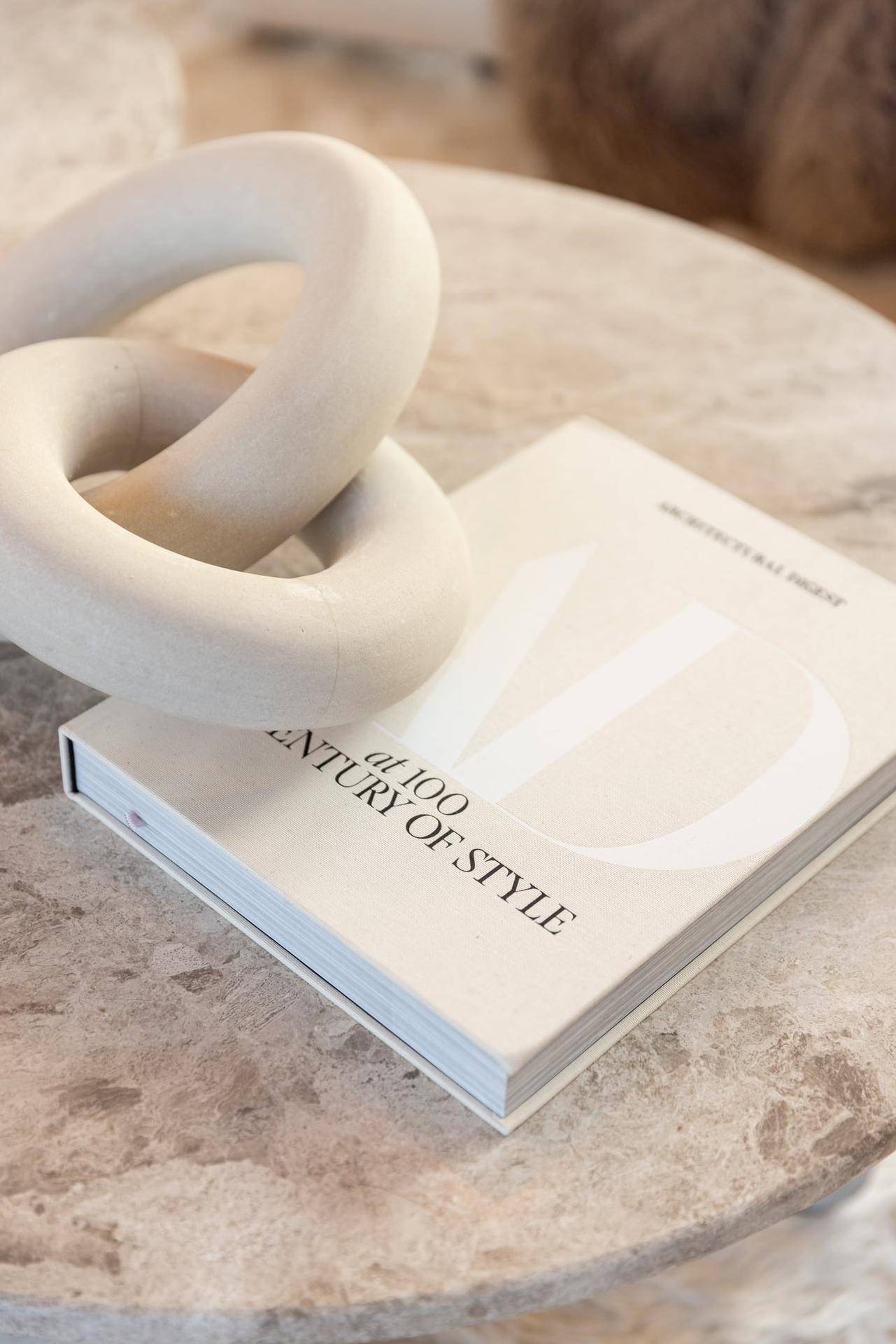 Detailaufnahme eines Couchtisches mit dekorativem Buch und stilvoller Holzskulptur.