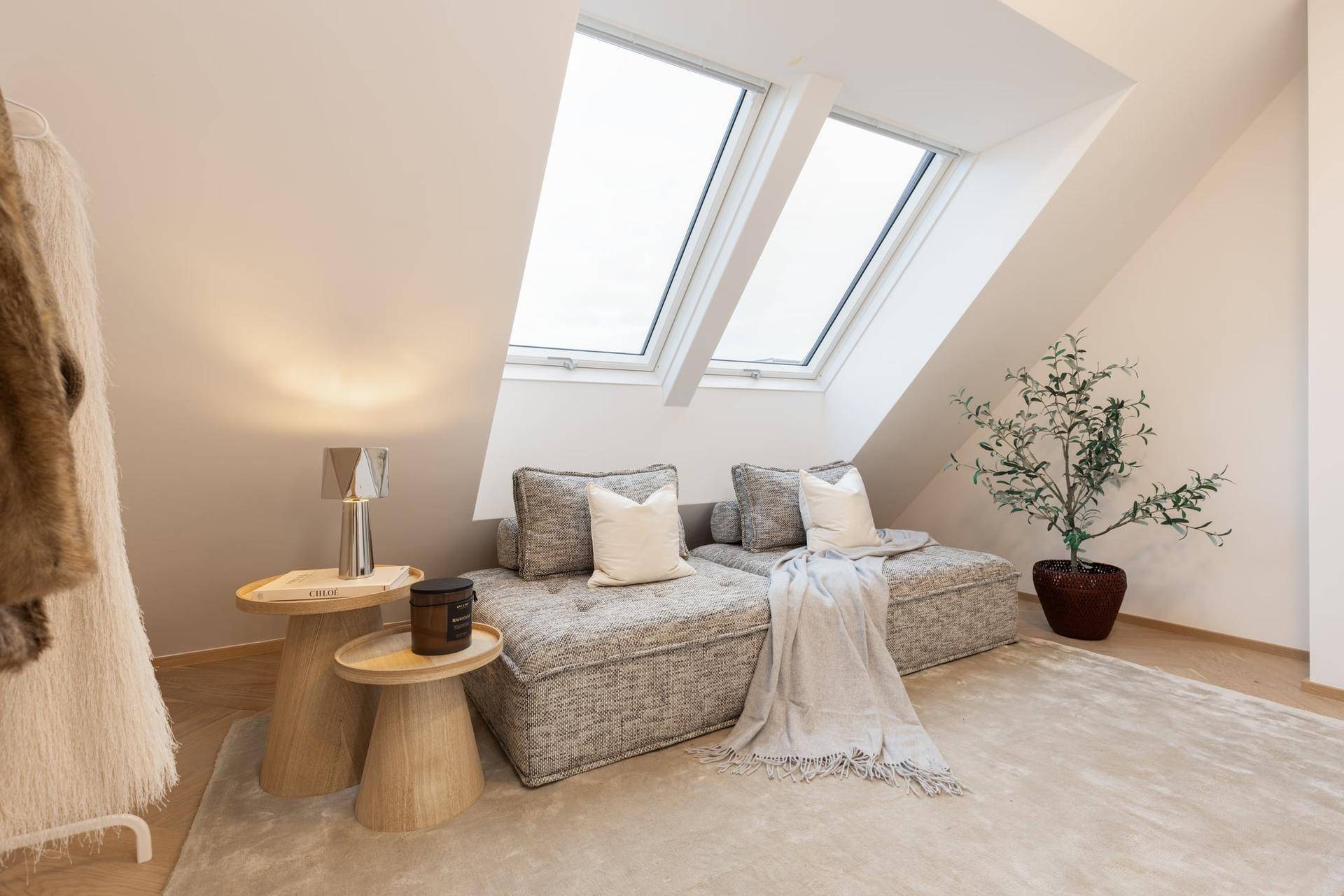 Gemütlicher Sitzbereich mit bequemer Couch, Beistelltischen und hellen Dachfenstern.