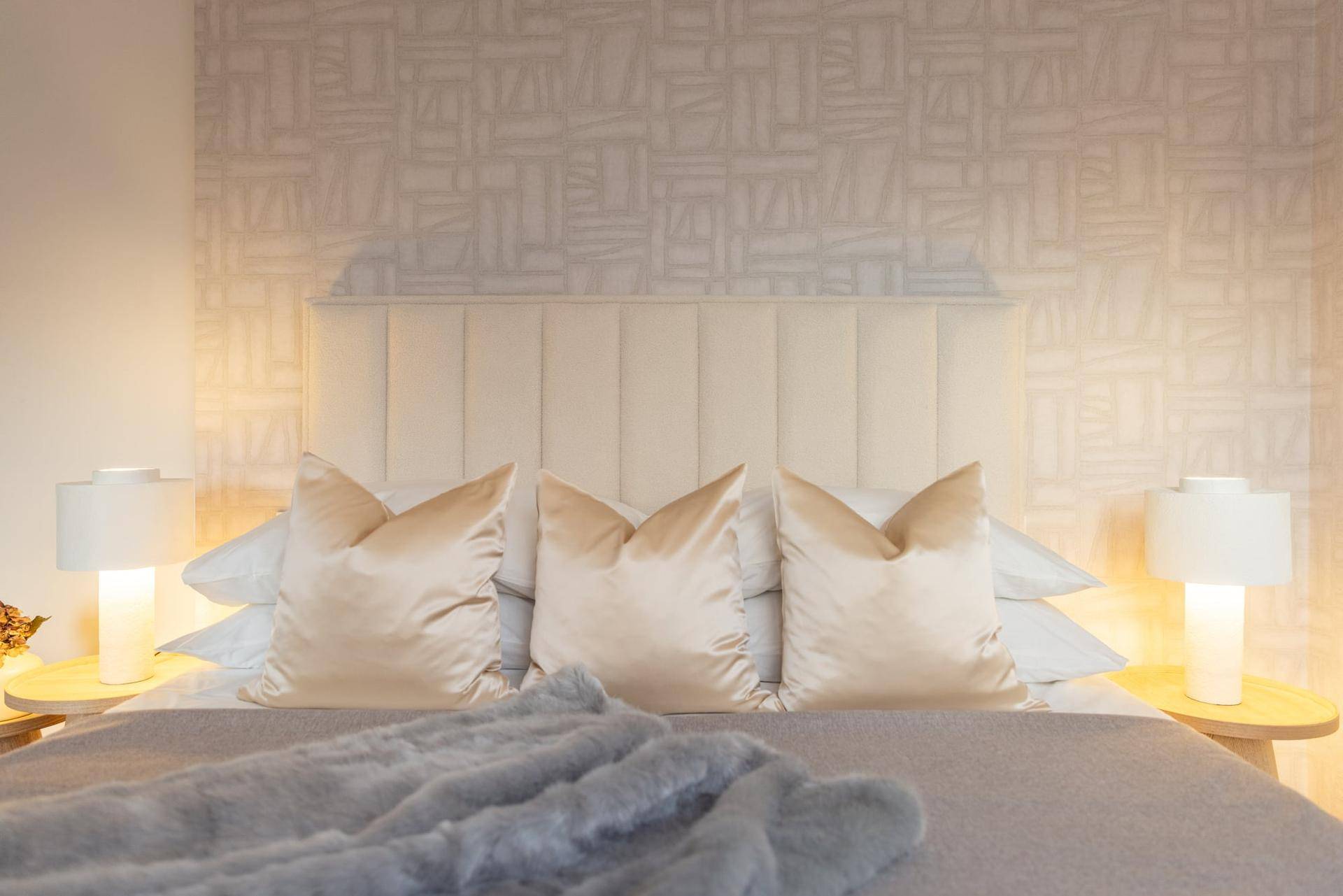 Nahaufnahme des Bettes mit bequemen Kissen, Decke und stilvollen Nachttischlampen.
