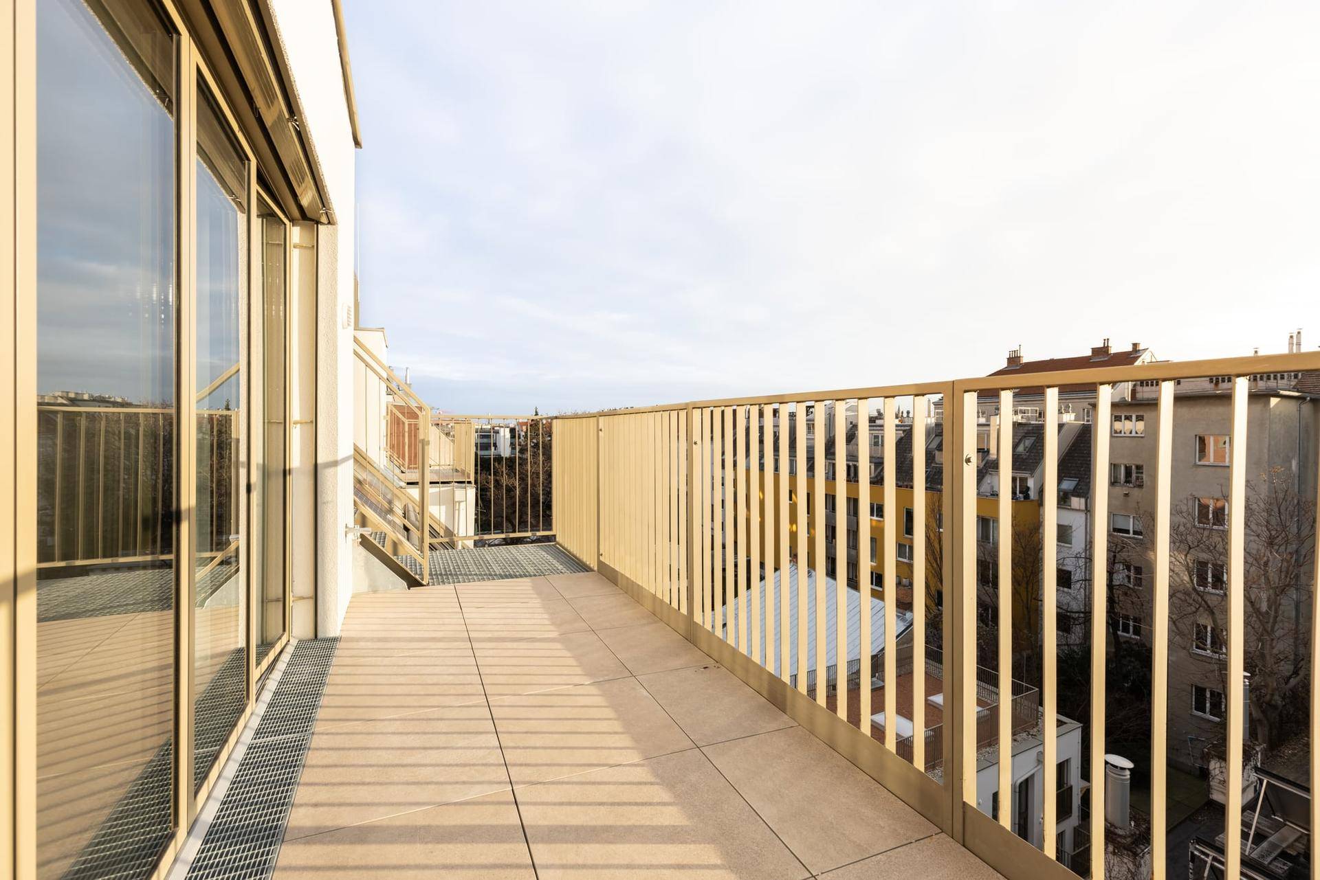 Lange Dachterrasse mit modernem Metallgeländer und weitem Blick über die städtische Umgebung.