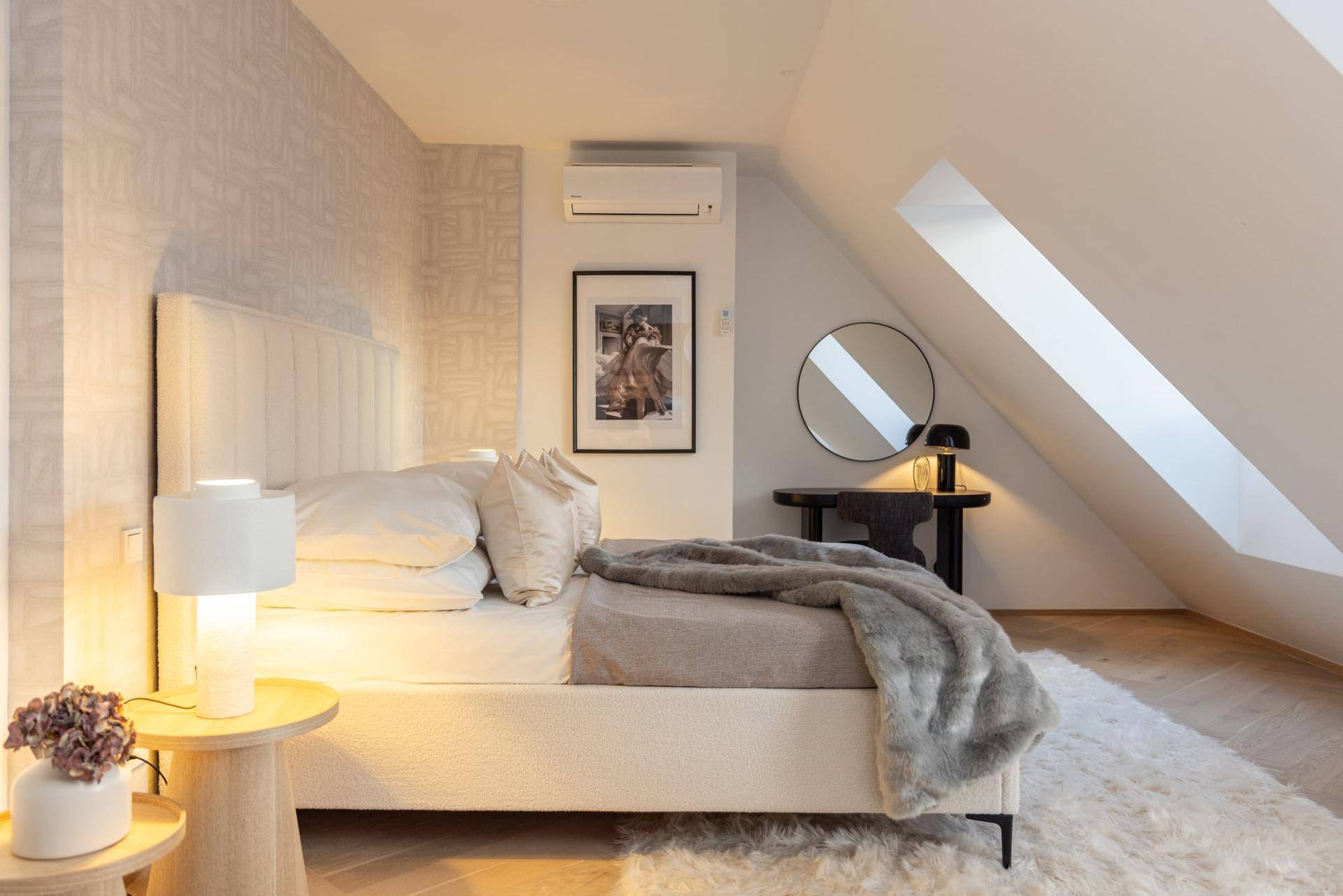 Helles Schlafzimmer mit großem Bett, gemusterter Tapete und schrägen Dachfenstern.