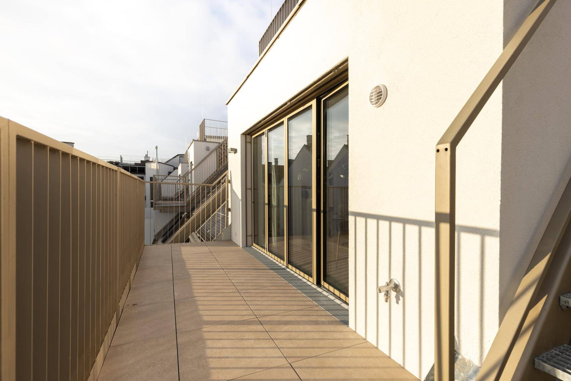 Helle Terrasse mit Glasschiebetüren, die den Zugang zum Innenbereich ermöglichen.