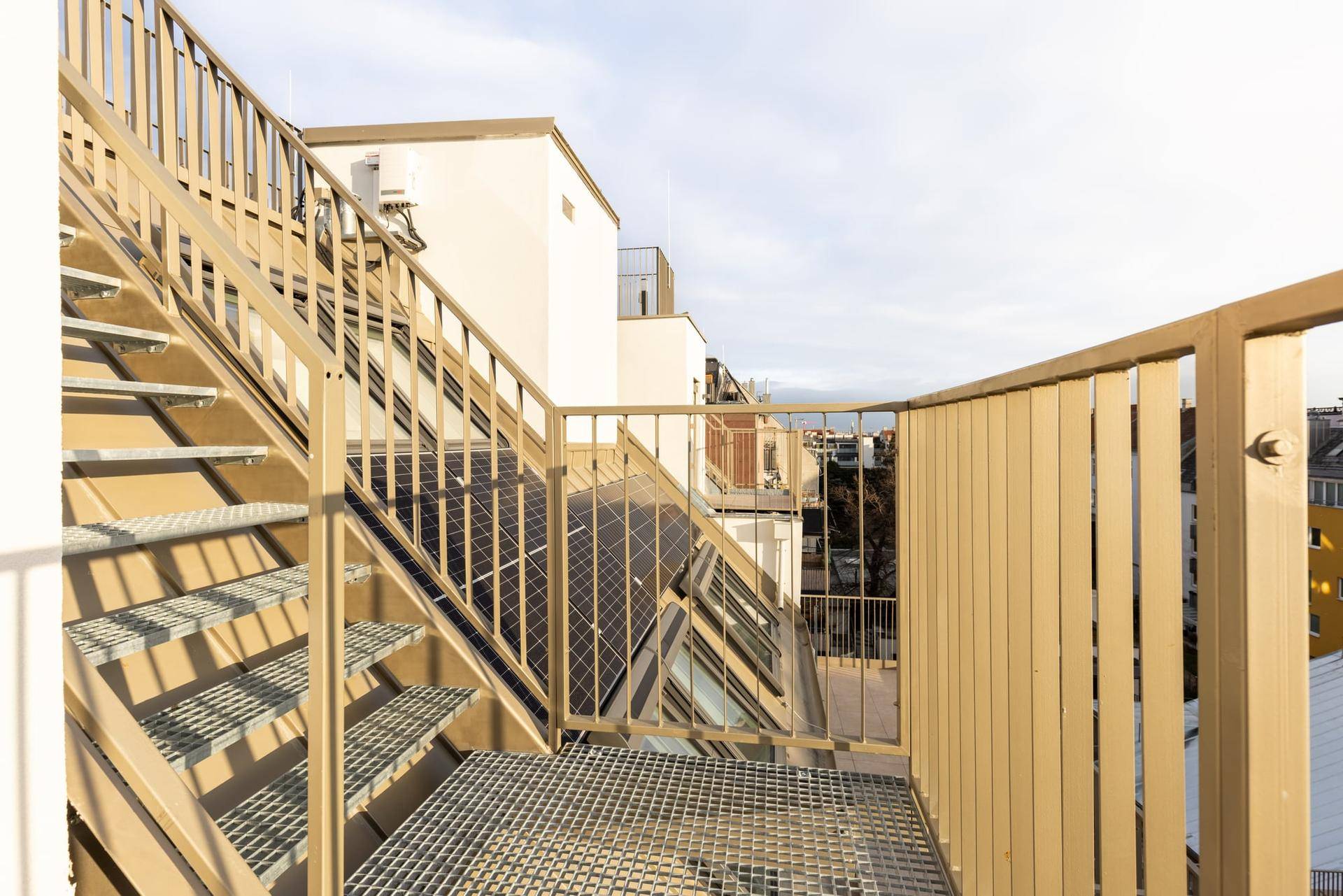 Robuste Metalltreppe führt zu einer weiteren Ebene der Dachterrasse mit Blick auf die Umgebung.