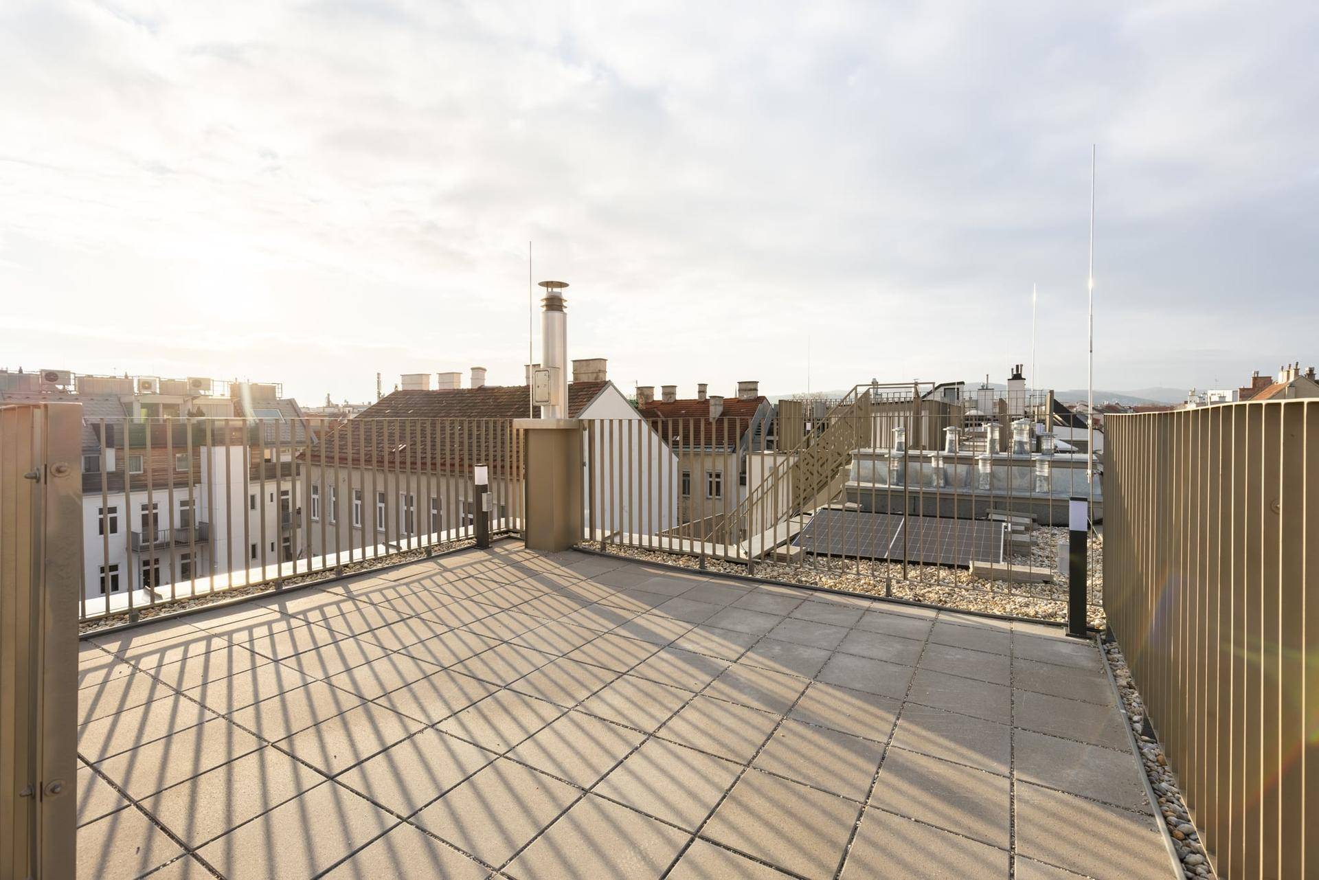 Weitläufige Dachterrasse mit Fliesenboden und modernem Geländer, ideal für Entspannung im Freien.