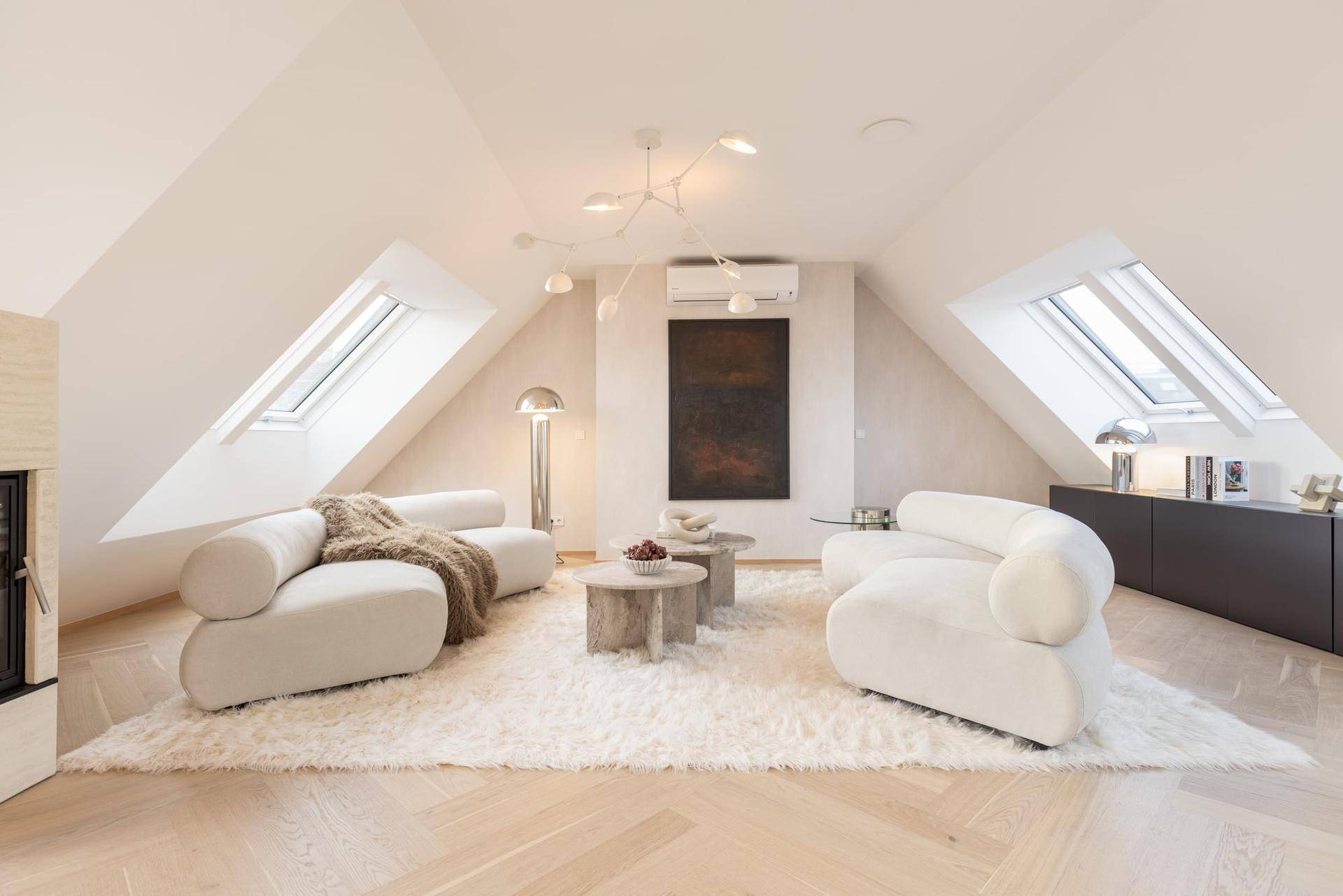 Gemütliches Wohnzimmer mit hellen Sofas, flauschigem Teppich und mehreren Dachfenstern für viel Licht.