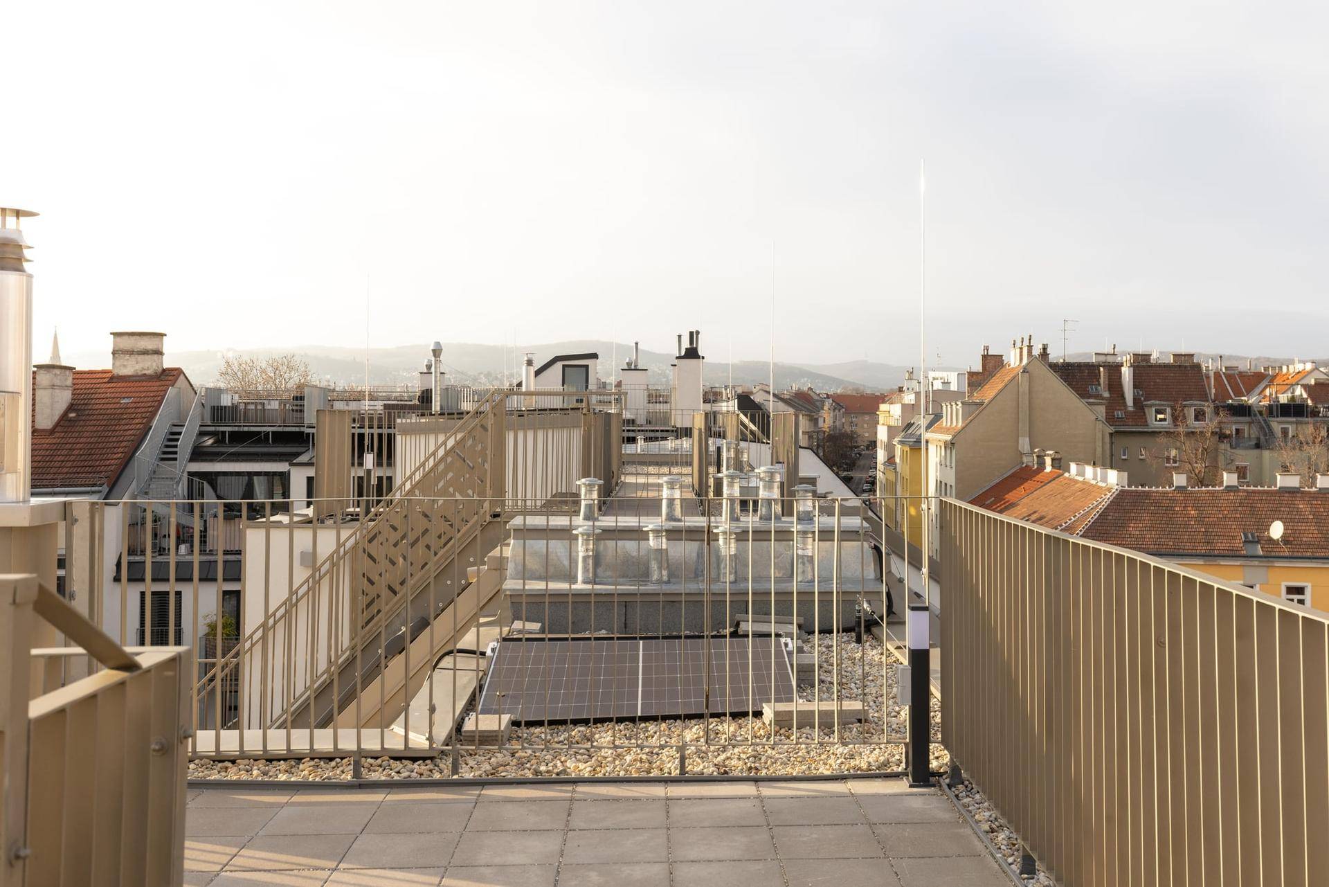 Dachterrasse mit Panoramablick über die Stadt und die umliegenden Hügel, Solaranlagen sichtbar.