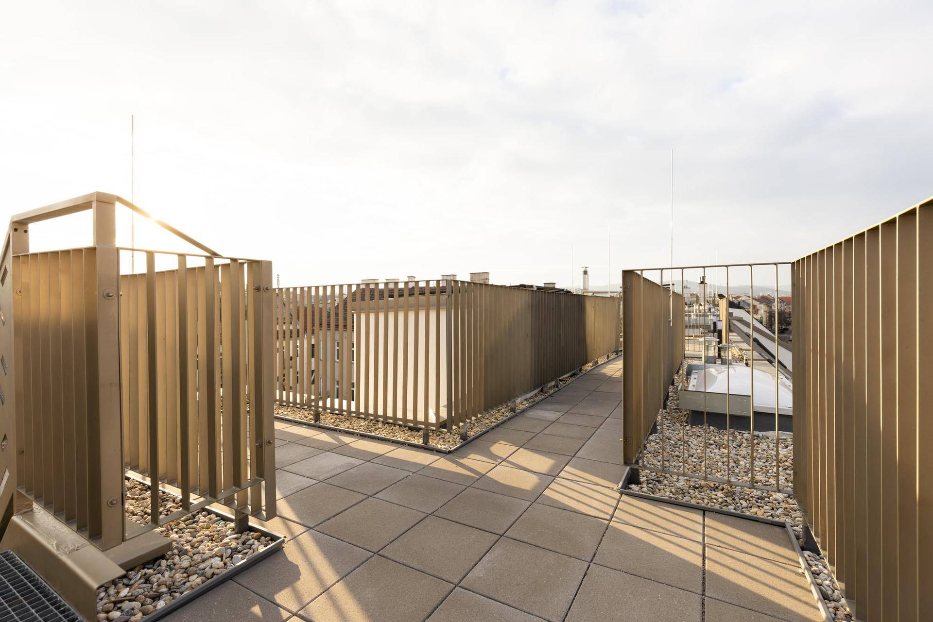 Weitläufige Dachterrasse mit Fliesenboden und Metallgeländer, bietet einen weiten Blick über die Stadt.