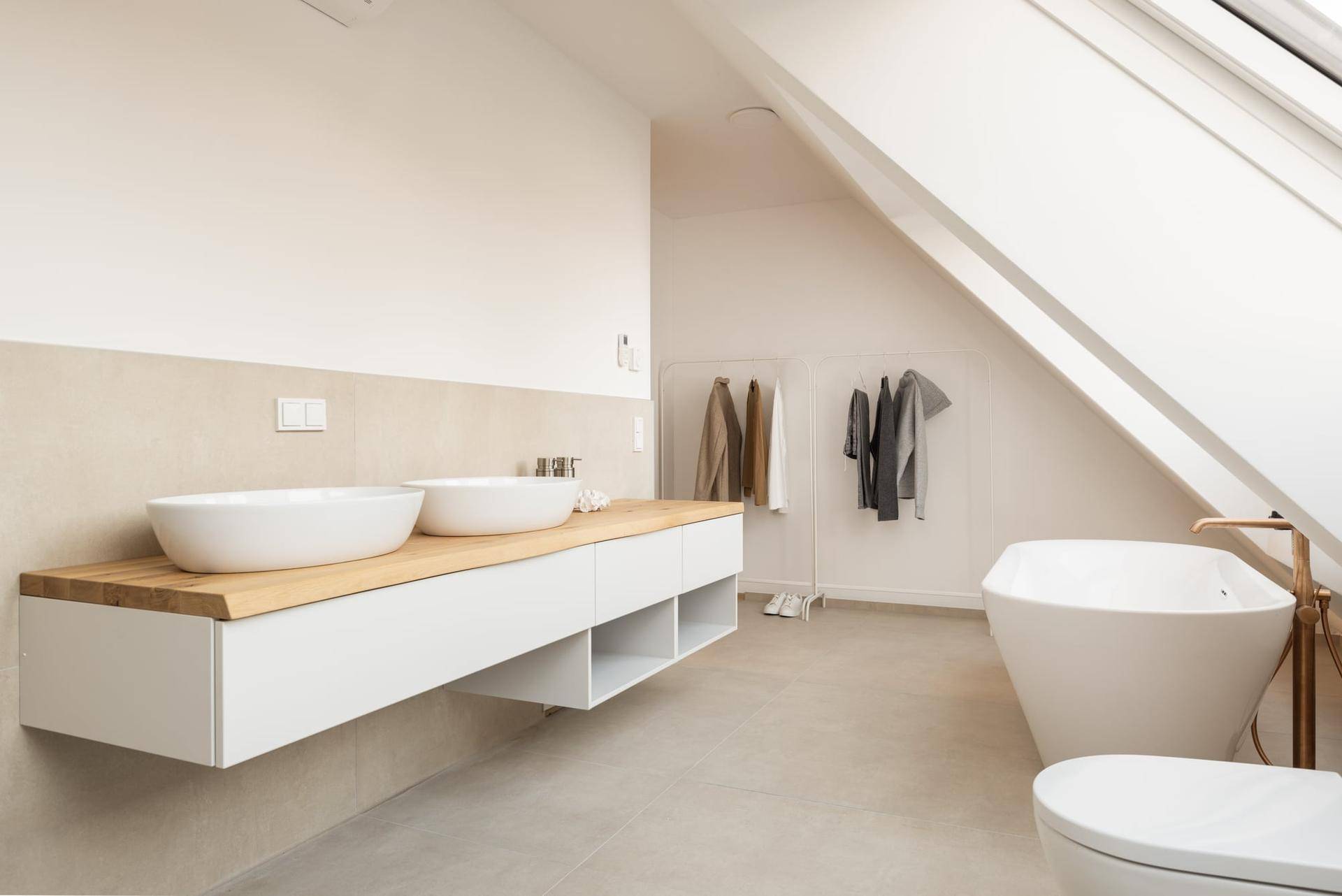 Luxuriöses Badezimmer mit Doppelwaschbecken, freistehender Badewanne und hellen Dachfenstern.