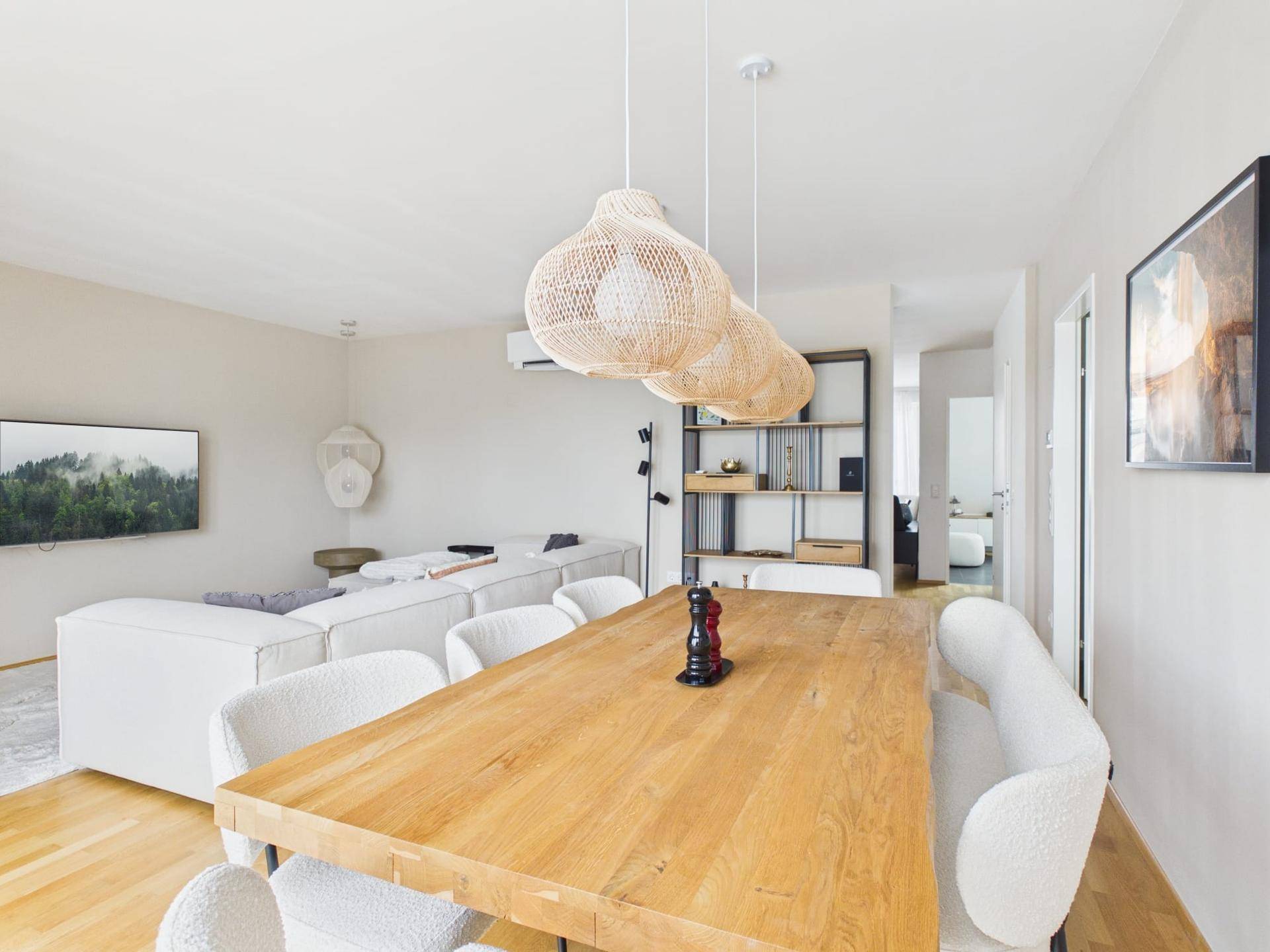 Heller Wohn- und Essbereich mit Holzboden, großem Esstisch und gemütlichem Sofa.