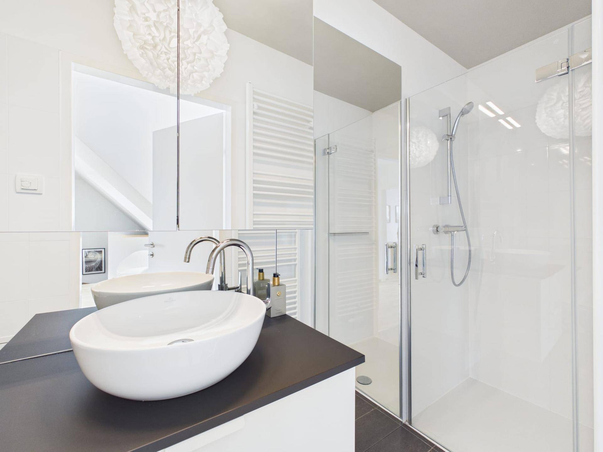 Modernes Badezimmer mit Doppelwaschbecken, großer Dusche und beheiztem Handtuchhalter.