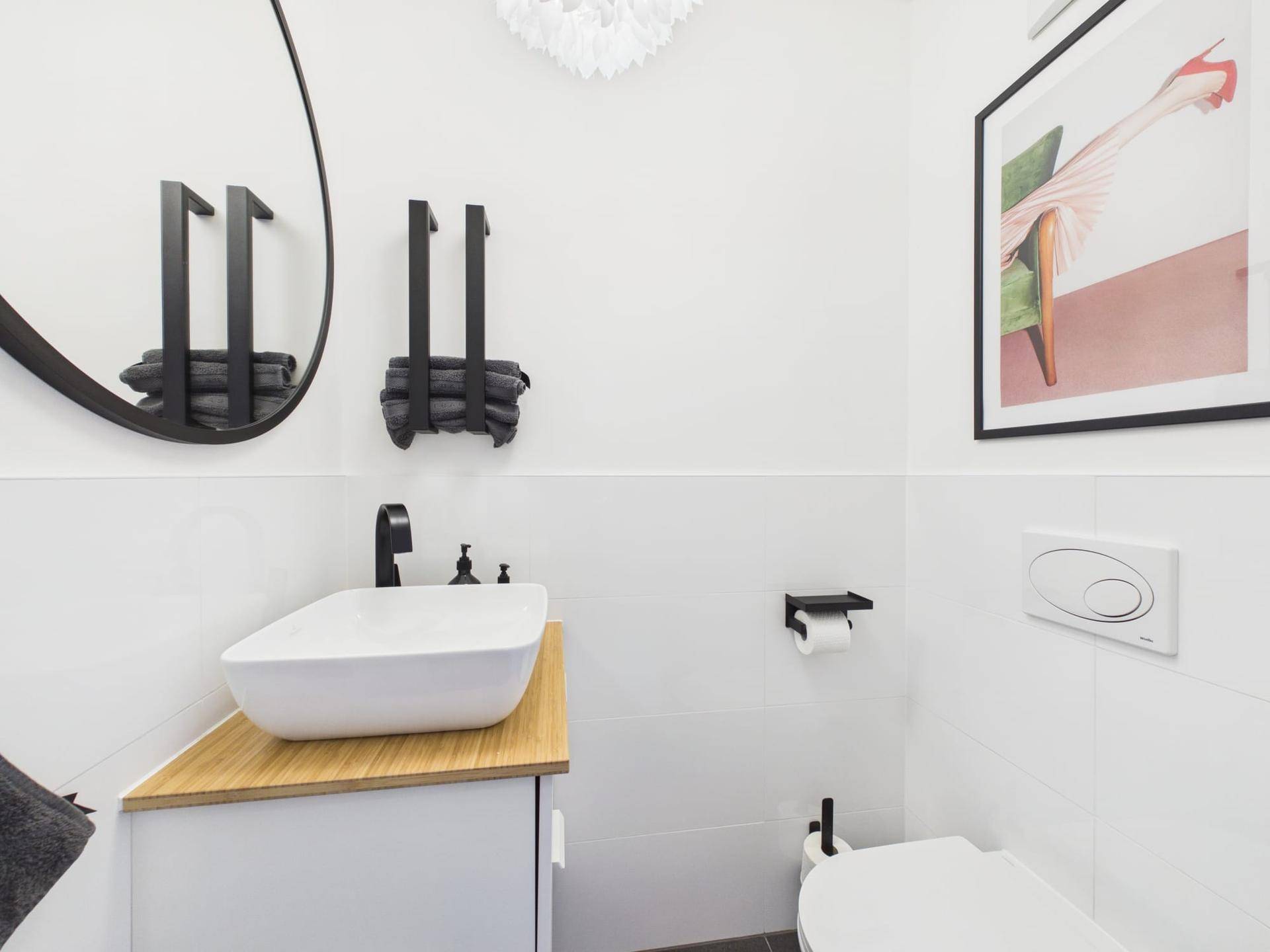 Modernes Gäste-WC mit weißer Wandverkleidung, Aufsatzwaschbecken und schwarzer Armatur.