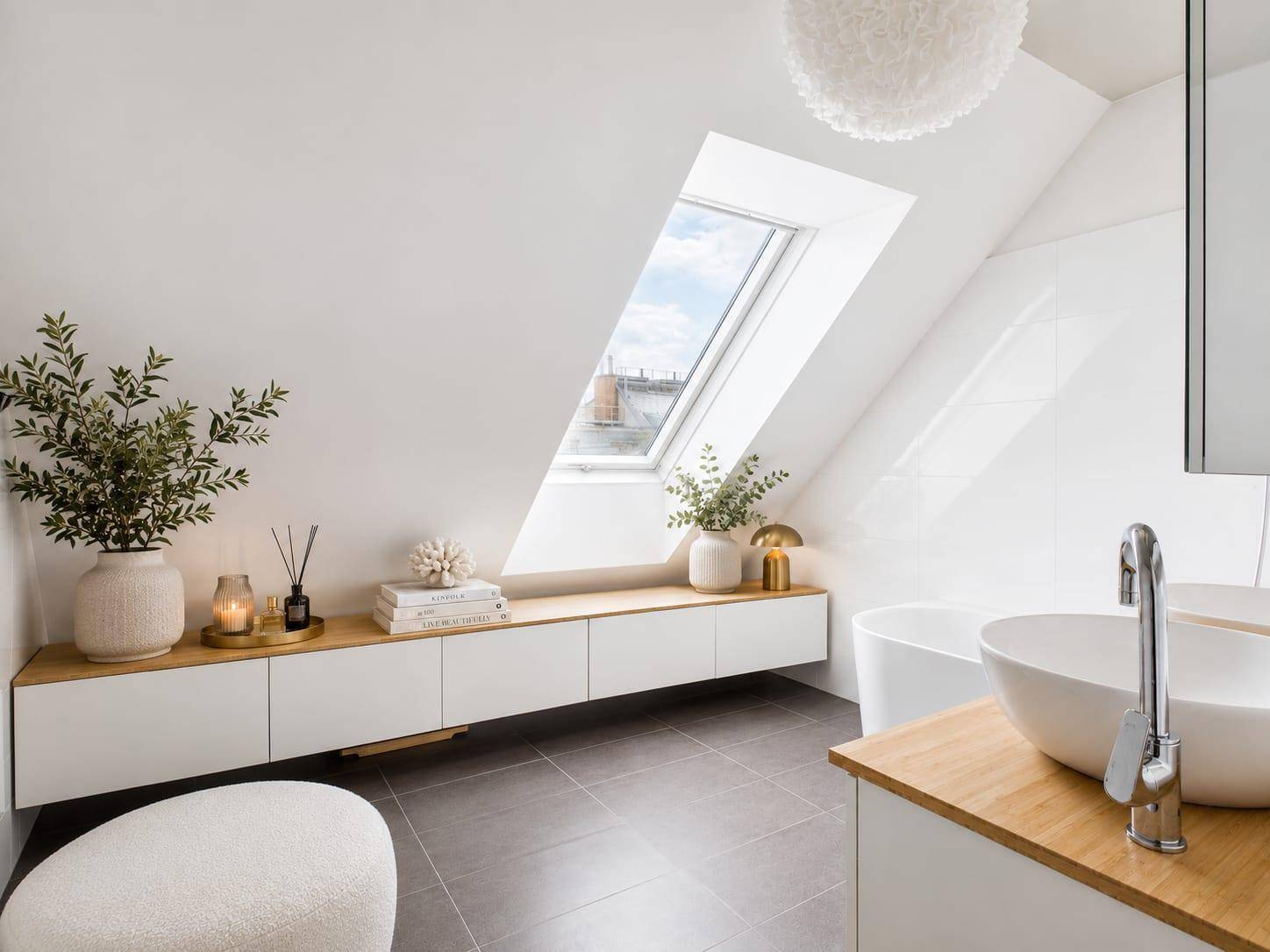 Modernes Badezimmer mit Dachfenster, Badewanne und schwebendem Waschtischunterschrank.