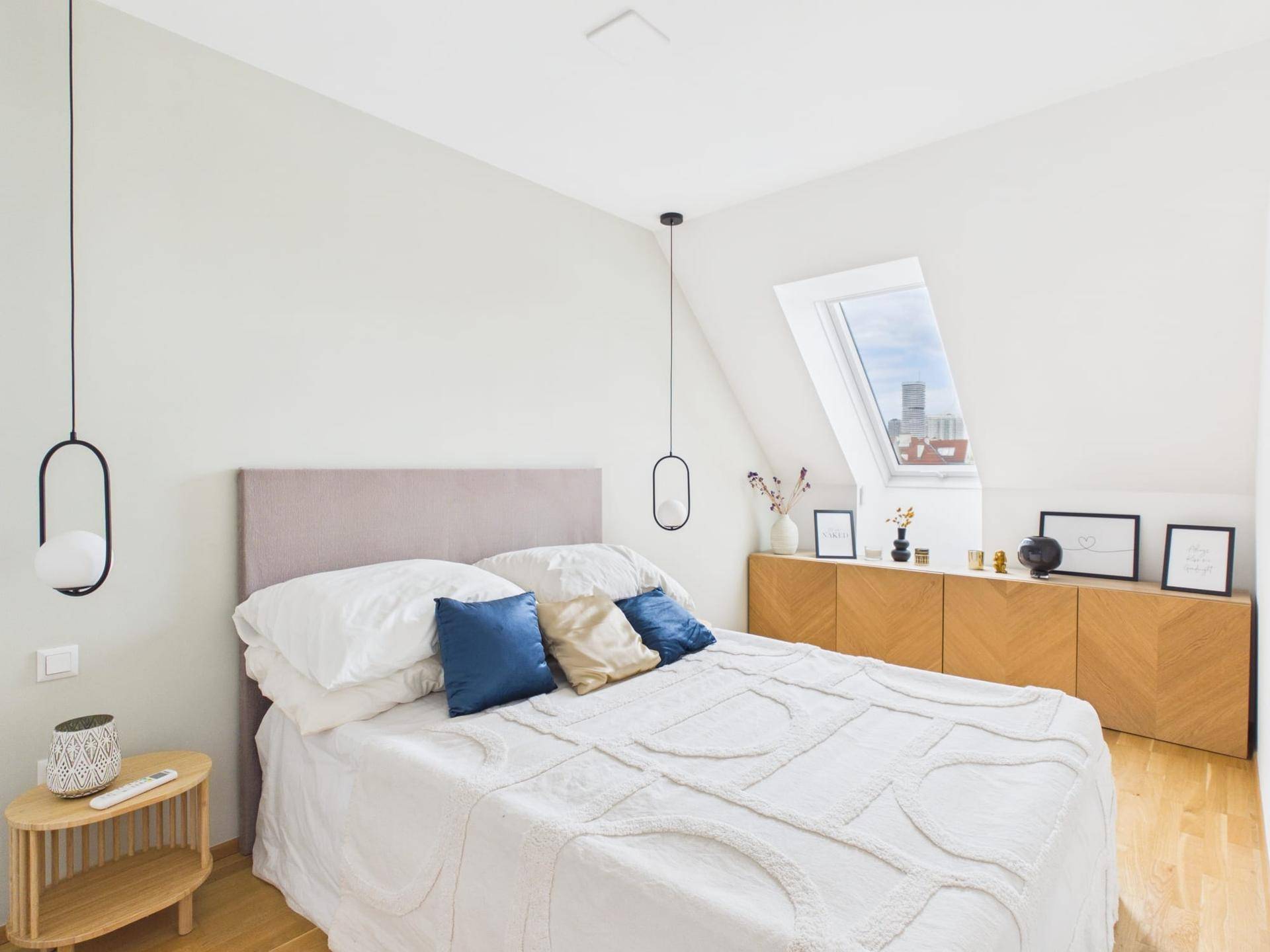 Helles Schlafzimmer mit Holzboden, Dachfenster und moderner Einrichtung.