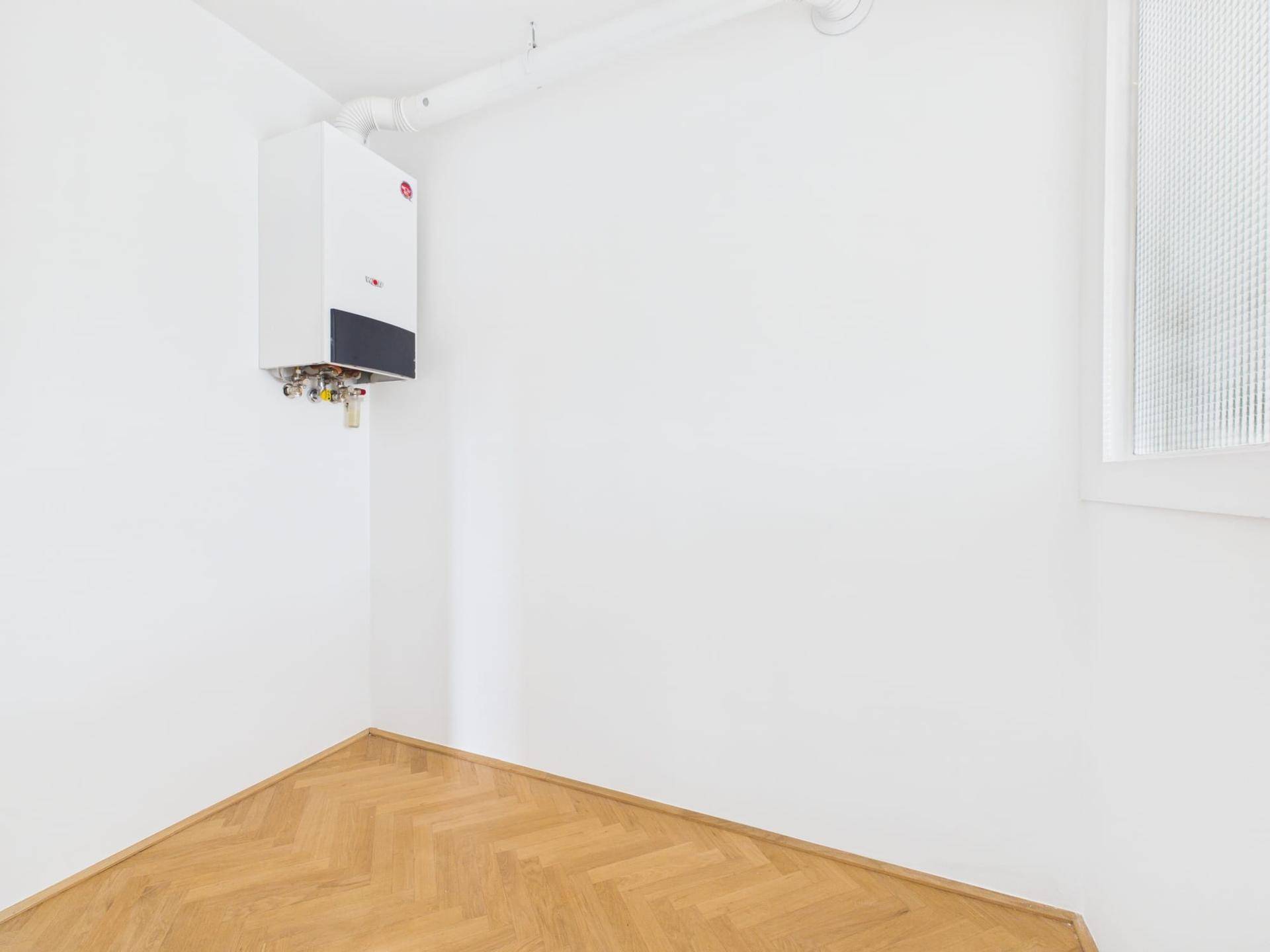 Hauswirtschaftsraum mit Wandheizkessel, Fischgrätparkett und einem Fenster für indirektes Licht.