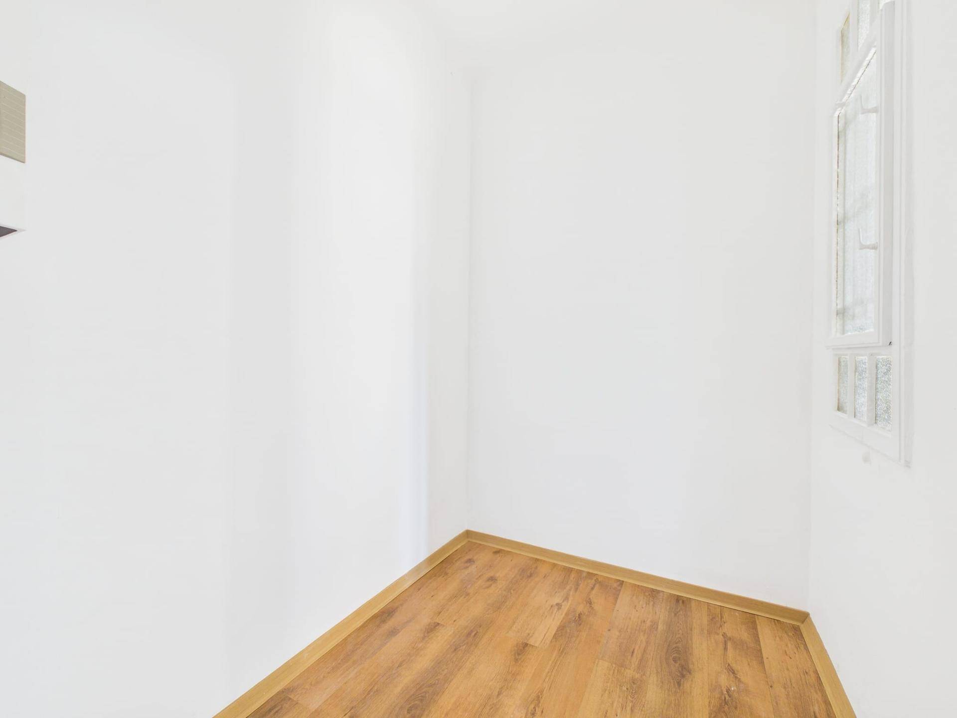 Kleiner, heller Raum mit Laminatboden und weißen Wänden, ideal als Abstellraum oder Kabinett.