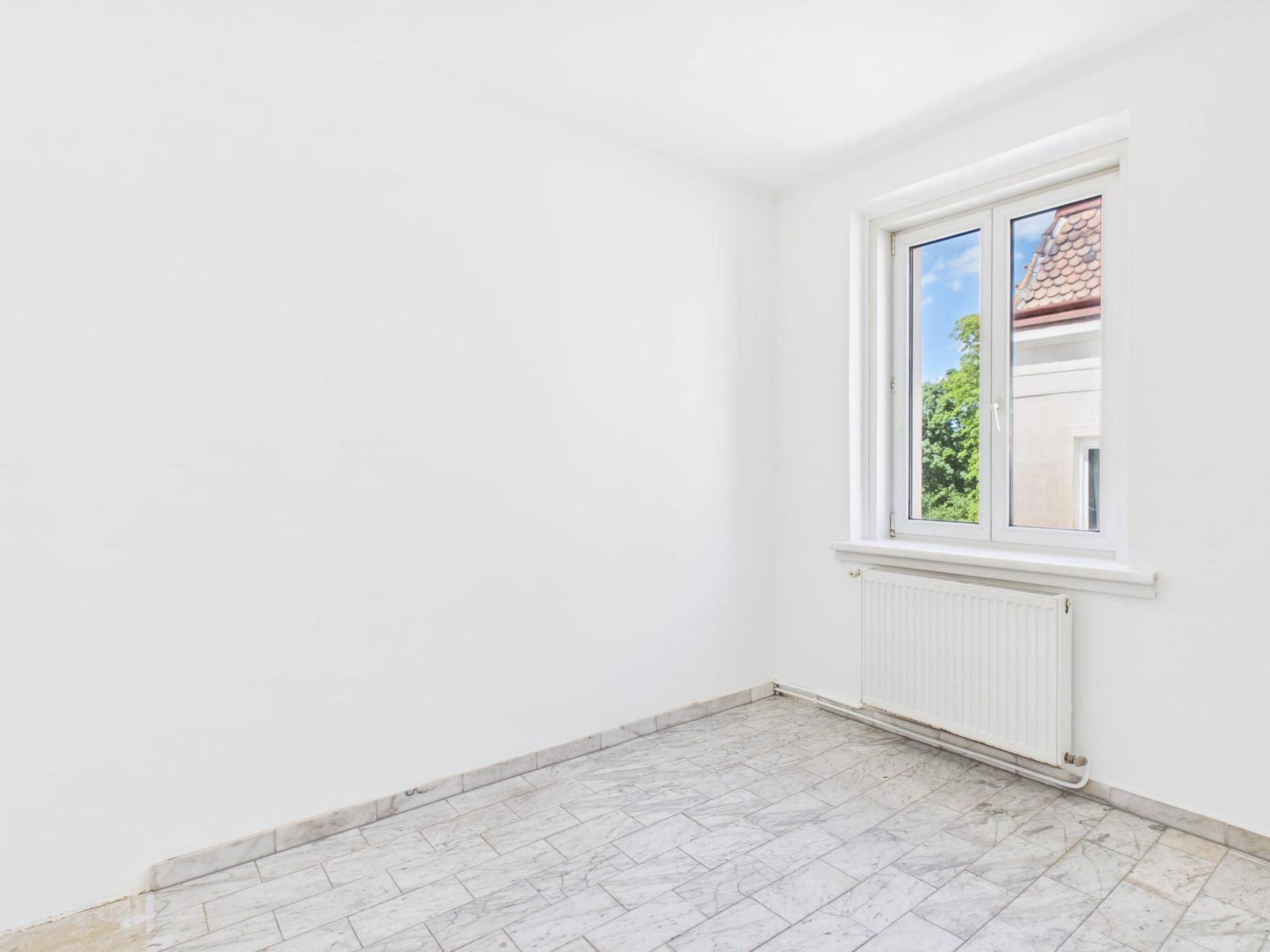 Leerer Raum mit hellen Fliesen und Fenster, das Tageslicht hereinlässt.