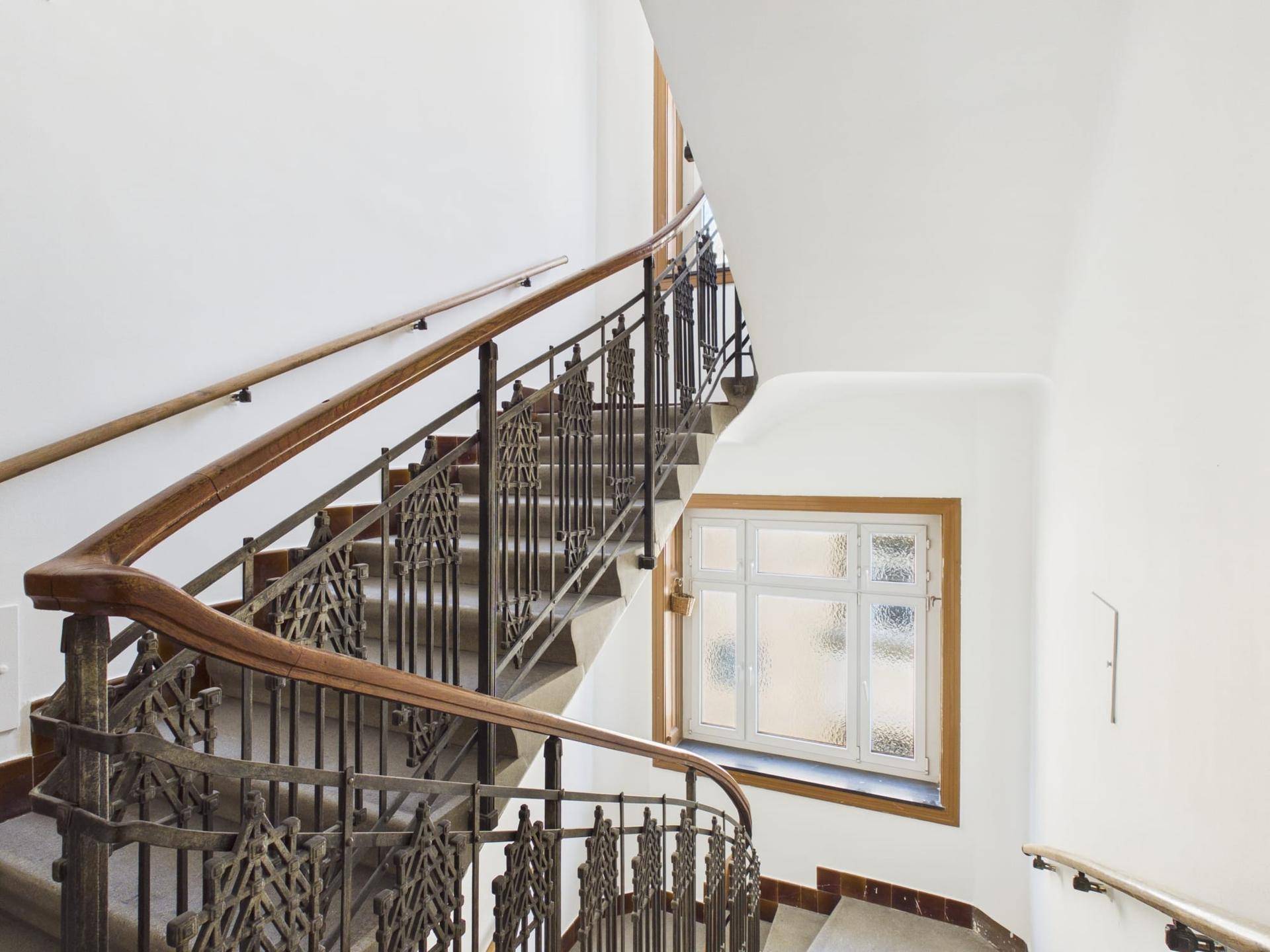 Historisches Treppenhaus mit kunstvollen Metallgeländern und Holzhandläufen, typisch für Altbauten.